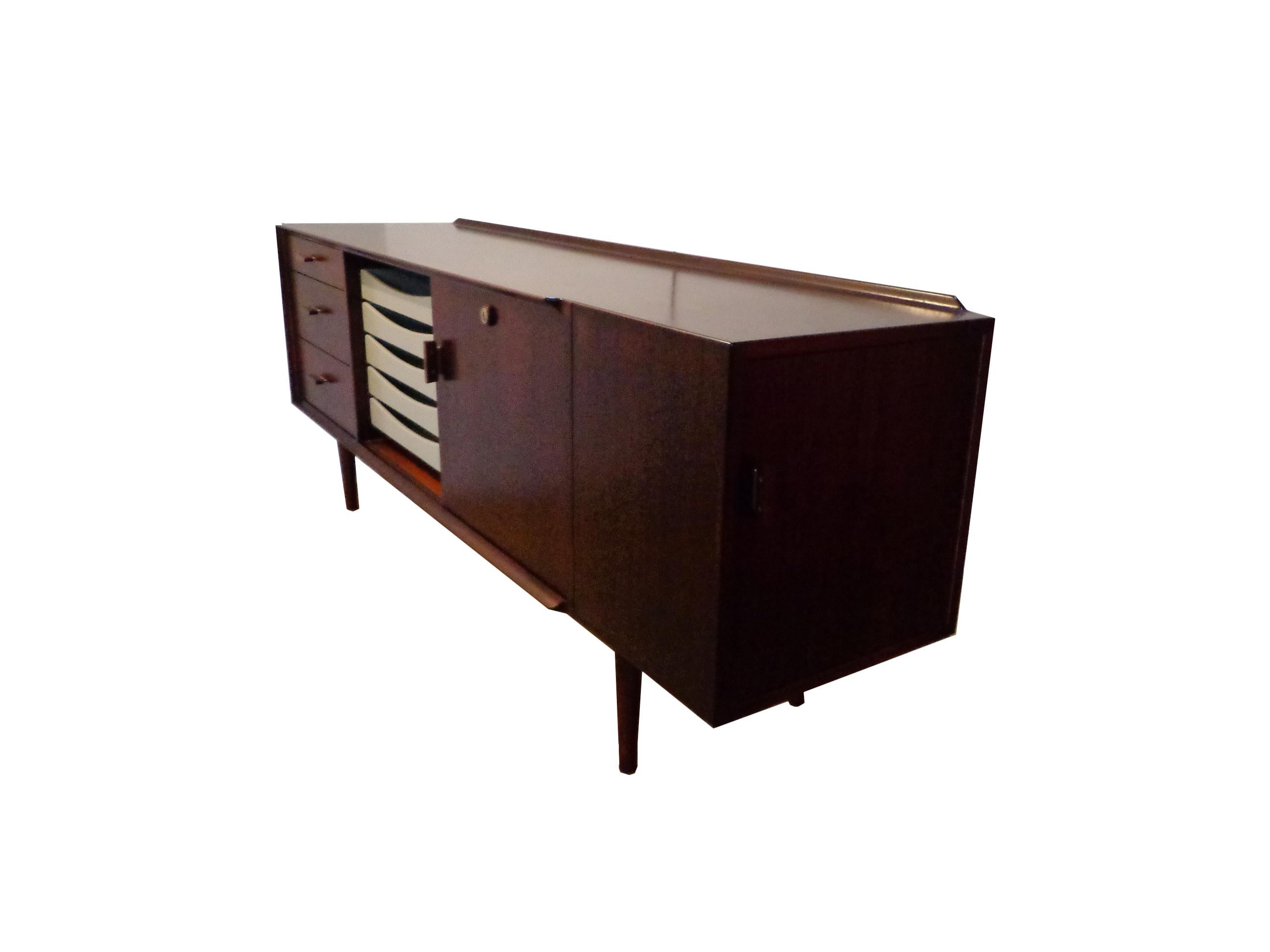Arne Vodder freestanding sideboard in Brazilian rosewood, top with profiled back edge. Front with three drawers, sliding door and five white coloured pull out trays. Handle with metal detail. Key included.