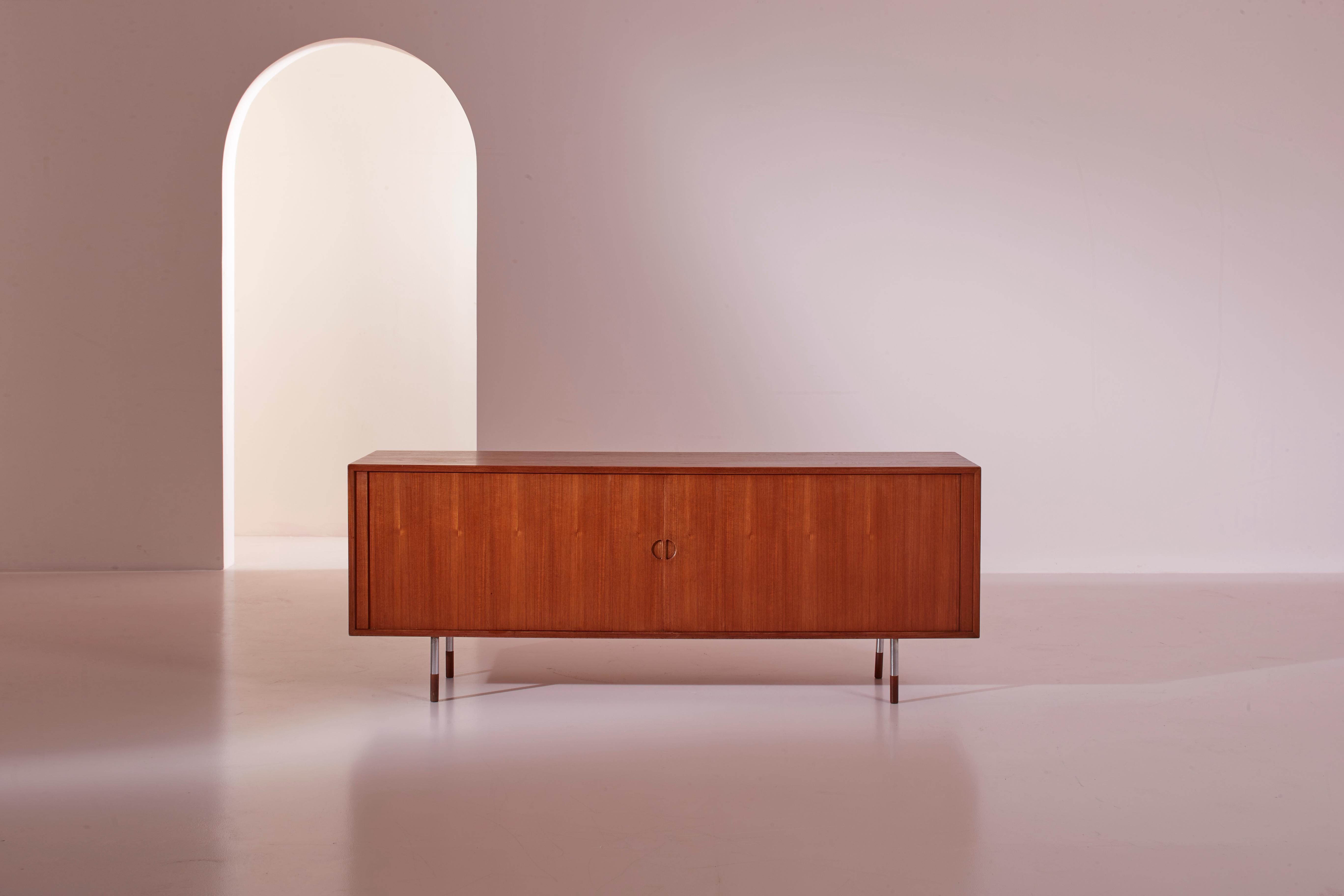 A well-proportioned sideboard crafted in teak and metal, dating back to the 1950s, bears the signature of the renowned designer Arne Vodder for Sibast Furniture, Denmark.

This elegant piece of furniture fully embodies the principles of simplicity