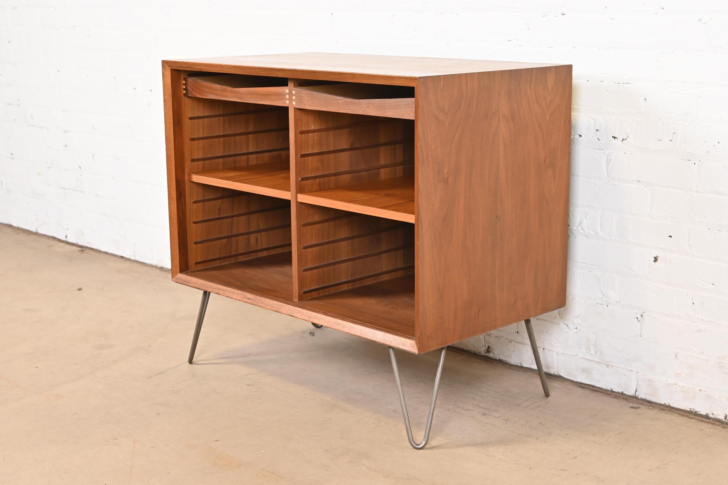 A sleek and stylish Mid-Century Danish Modern bookcase, record cabinet, or bar cabinet

In the manner of Arne Vodder

Denmark, Circa 1960s

Walnut, with steel hairpin legs. Shelves and drawers are adjustable and removable.

Measures: 31.5