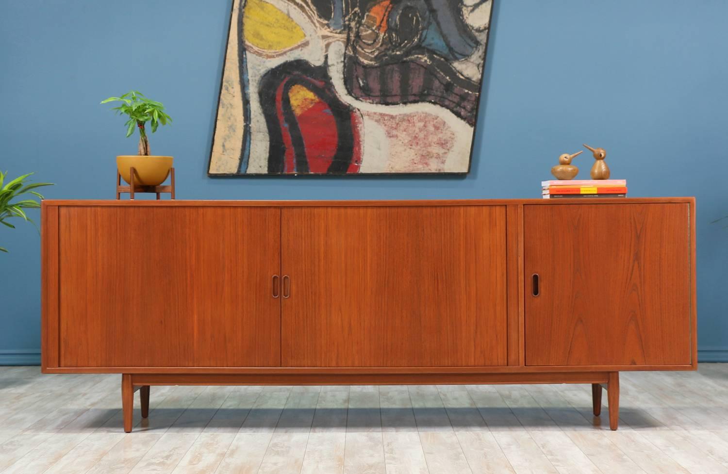 Danish Modern teak credenza designed by Arne Vodder for Sibast Møbler in Denmark circa 1950’s. This impressive credenza features a teak wood frame with two tambour doors that slide open smoothly to reveal six dovetailed trays positioned in the