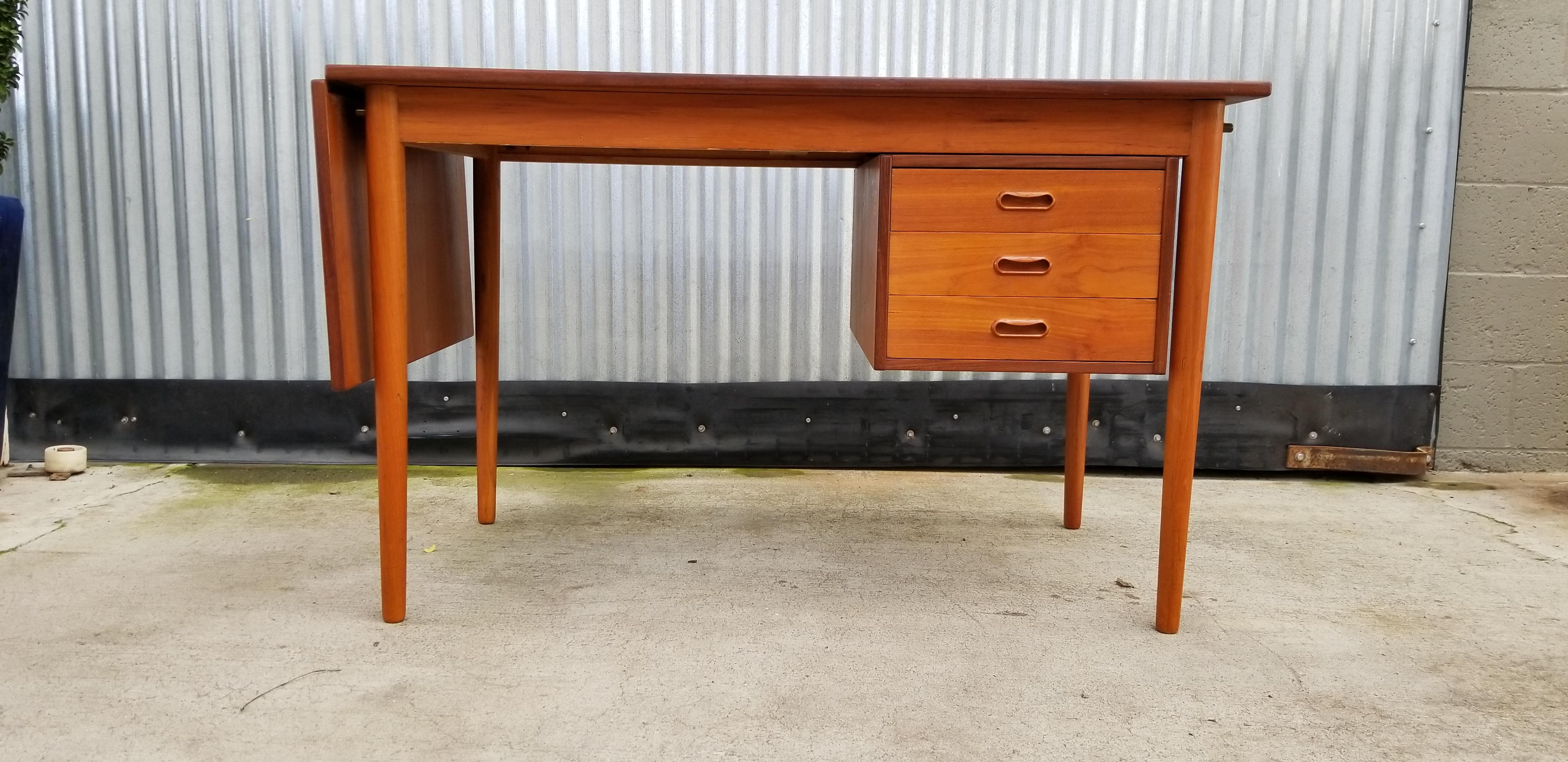 A Danish modern teak desk designed by Arne Vodder, circa 1960s. Featuring a sliding drawer unit that allows use as a right or left handed desk. Sliding top surface with a drop-leaf extension adds versatility to work surface. Classic Danish