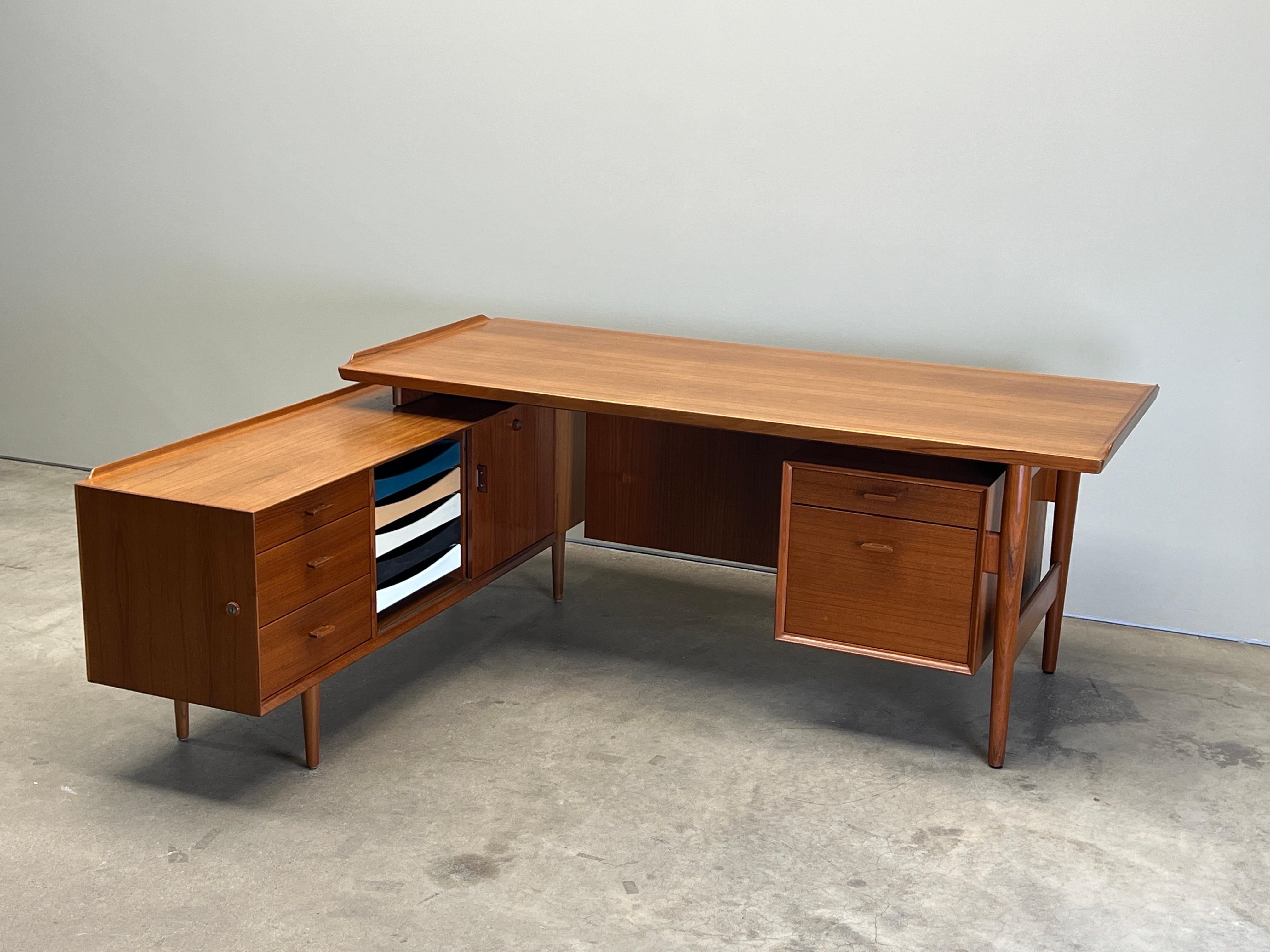 Un'ampia scrivania in teak con ritorno disegnata da Arne Vodder per Sibast. 
