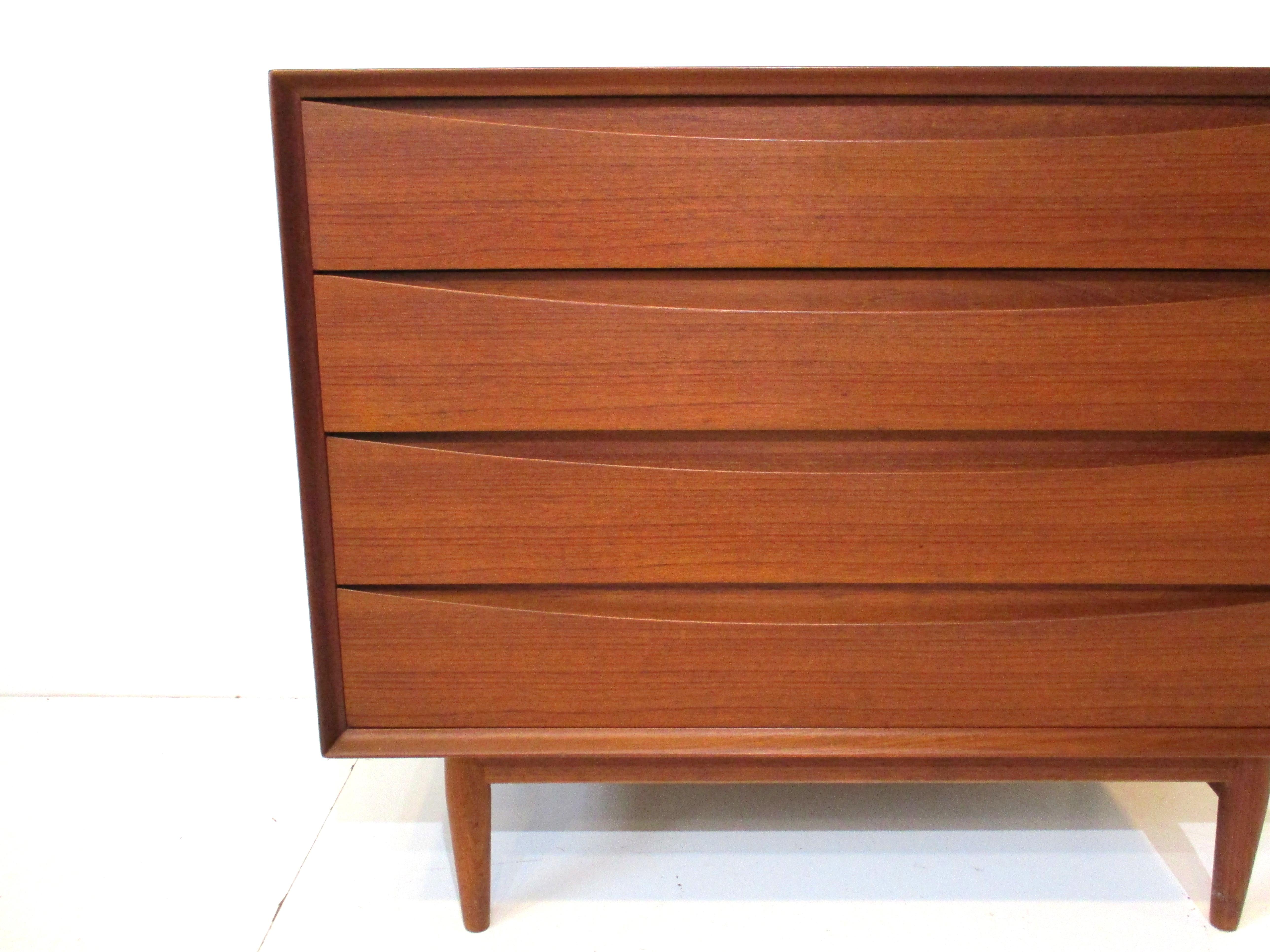 A very well crafted teak four drawer dresser chest with cats eye drawer fronts which was a signature statement of the iconic designer Arne Vodder. Matching teak conical legs with cross stretchers make the piece sturdy and the backside is finished in