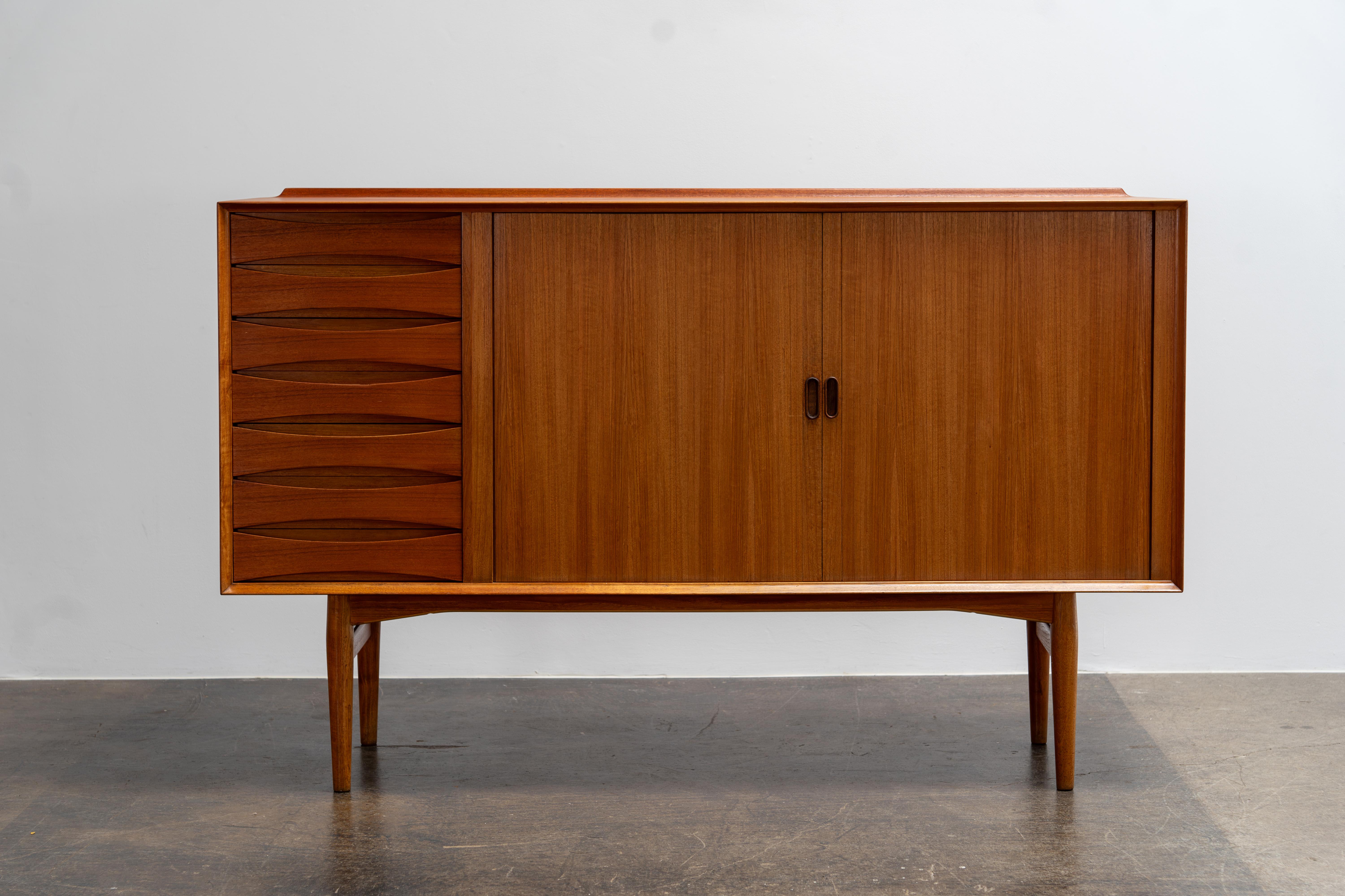 Arne Vodder - Credenza in teak
Sibast, Danimarca, anni '50

Questa elegante credenza, disegnata da Arne Vodder per Sibast negli anni '50, esemplifica la raffinata estetica moderna danese dell'epoca. Realizzato in caldo legno di teak, il mobile è
