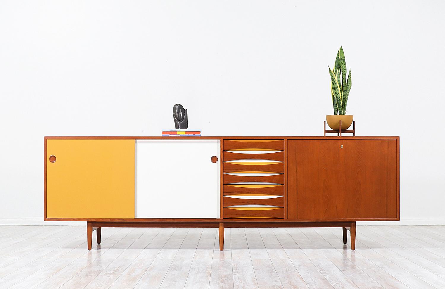 Danish modern teak credenza designed by Arne Vodder for Sibast Møbler in Denmark in 1959. This impressive model 29A credenza features a teak wood case with sliding doors and a shelved interior, seven drawers in the middle, and a pull-down