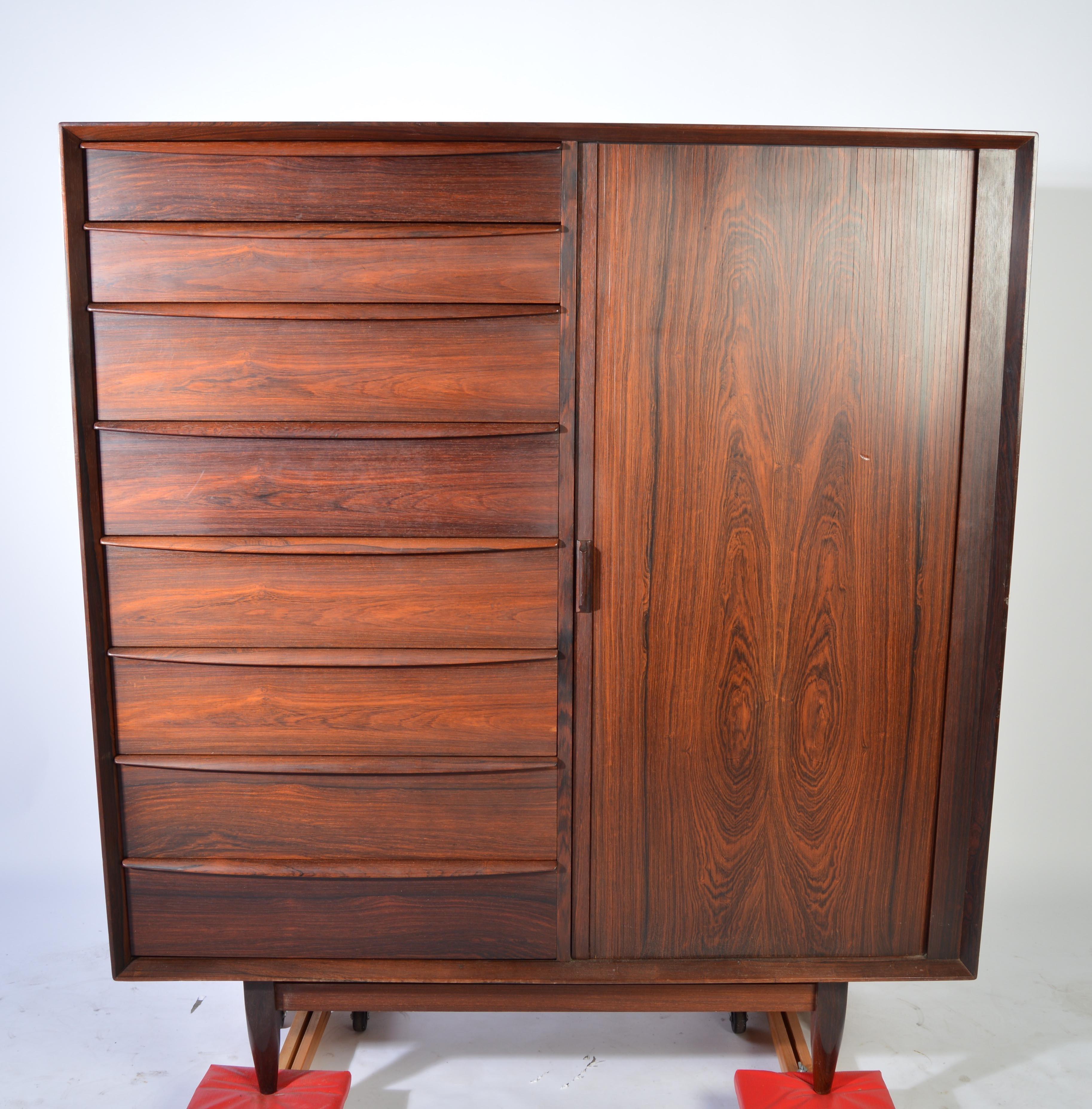 A stunning chest of drawers in Brazilian rosewood designed by Svend Madsen for Falster Denmark having 8 drawers on the left and 9 drawers on the right which are tucked behind a top to bottom Tambour door.
Quite beautiful in rosewood.
Great overall