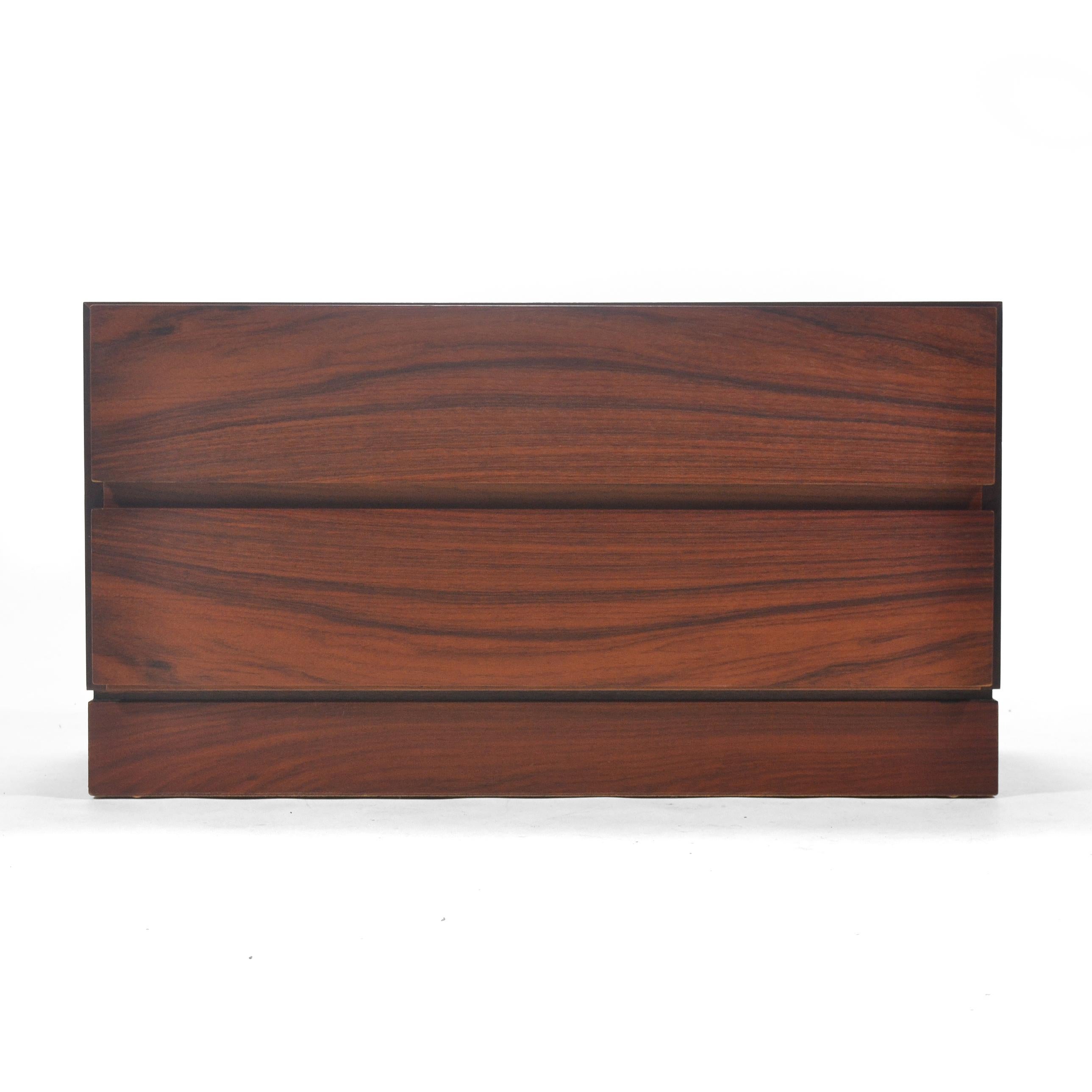 This handsome Danish two-drawer cabinet designed by Arne Wahl Iversen for Vinde Mobelfabrik is clad in beautiful, rich rosewood, has a plinth base, and an unusual scale which also allows it to serve as a riser, a pedestal, or end table.