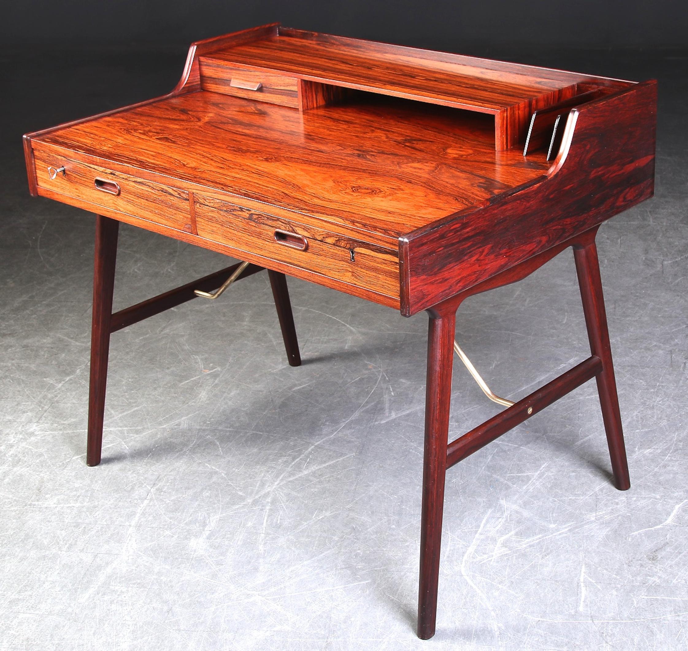 A desk in rosewood veneer designed by Arne W. Iversen and edited by Vinde Mobelfabrik in the 1970s.Top with drawer; compartiment and letter sortens, front with two drawers; tramsons in brass. Key included. Stamped with ink stain on the underside.