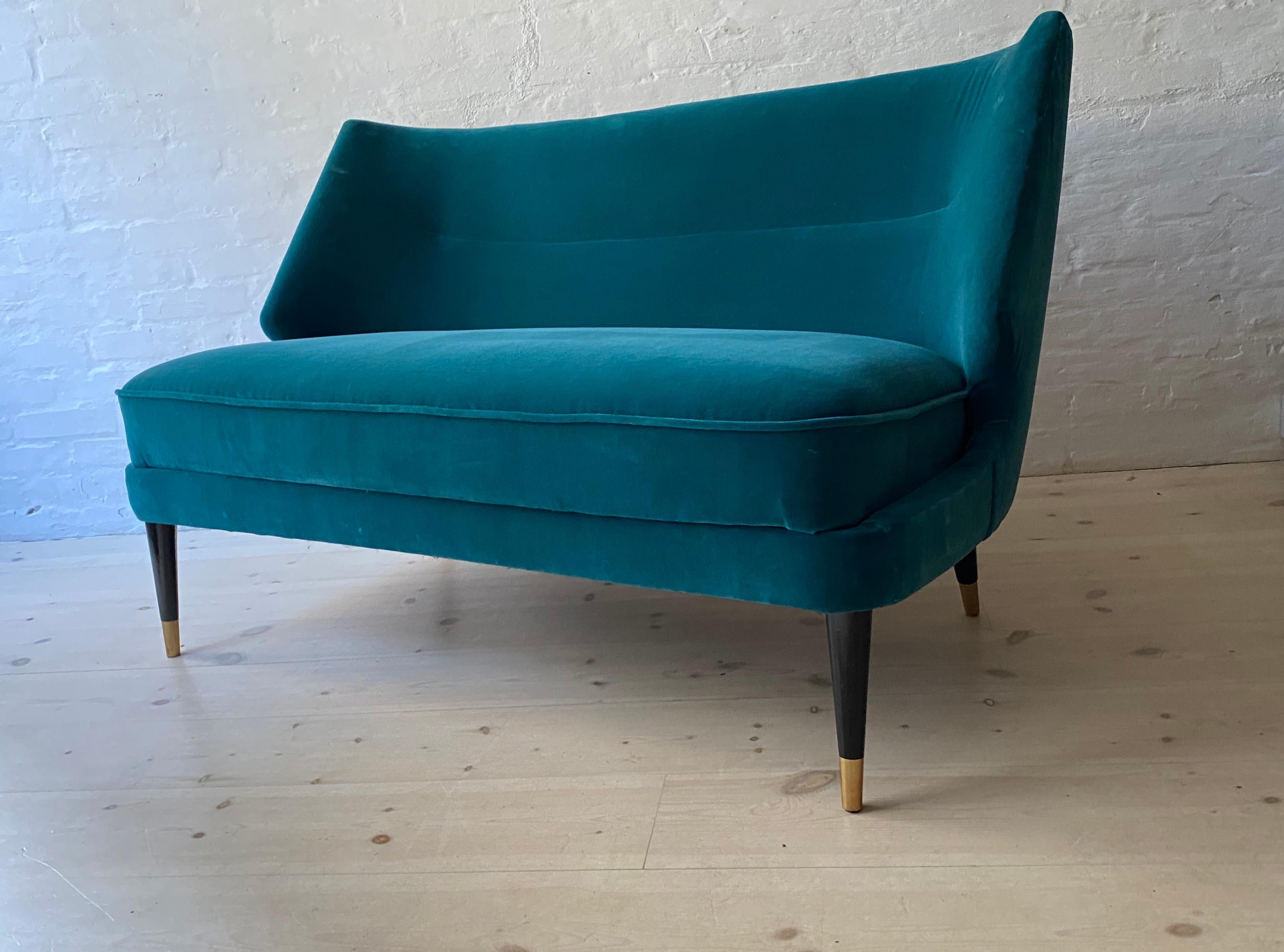 A Danish upholstered sofa by Arne Wahl Iversen, circa 1950-1960, with a angular and curved back, drop-in upholstered seat raised on ebonized circular tapered legs ending with brass caps.
Recently upholstered in petrol color velvet.