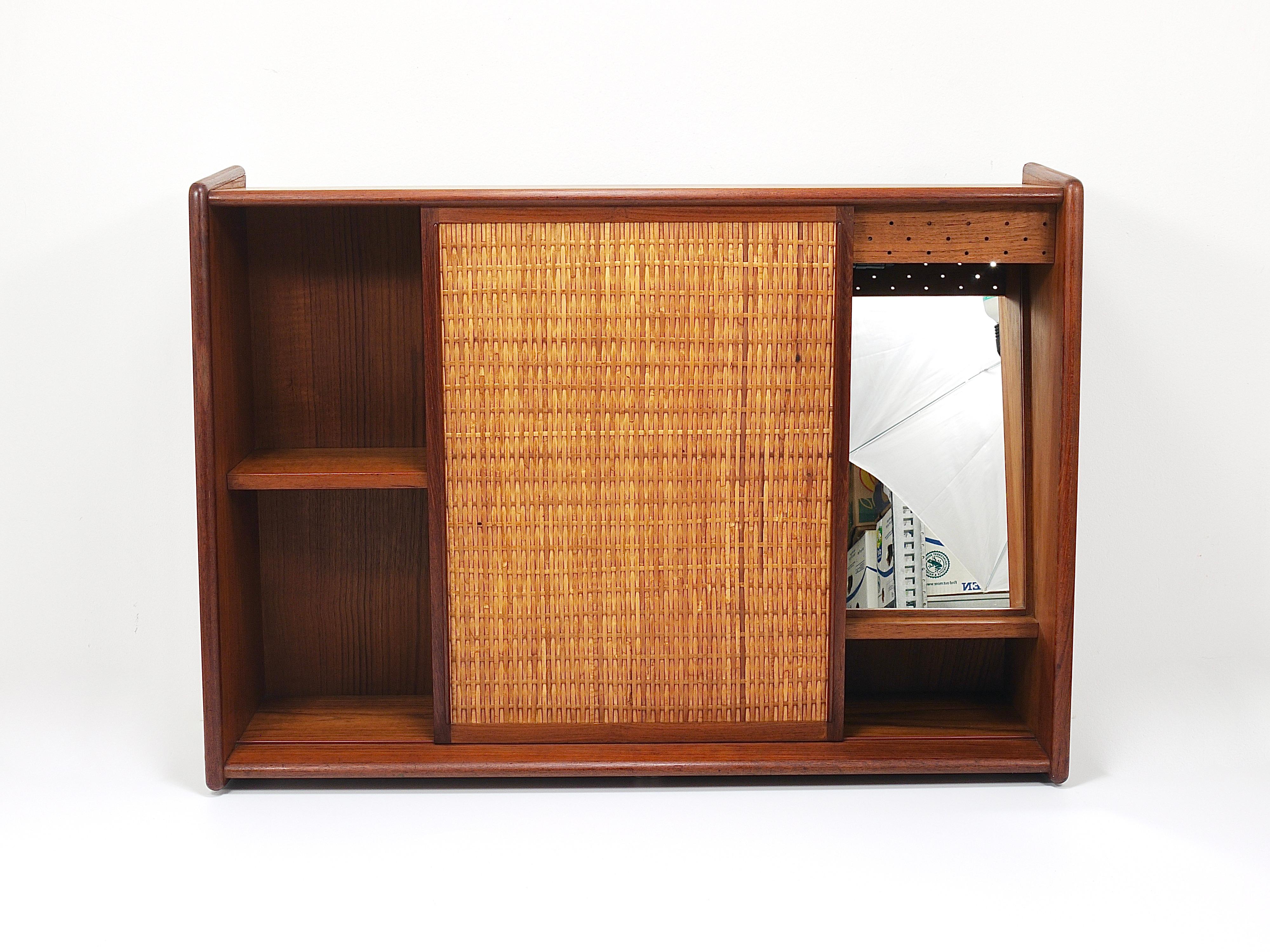 This beautifully restored Mid-Century Danish Modern wall-mounted hallway cabinet, designed by Arne Wahl Iversen and manufactured by Brenderup Møbelfabrik in Denmark, combines functionality and aesthetics. It features an illuminated vanity mirror,