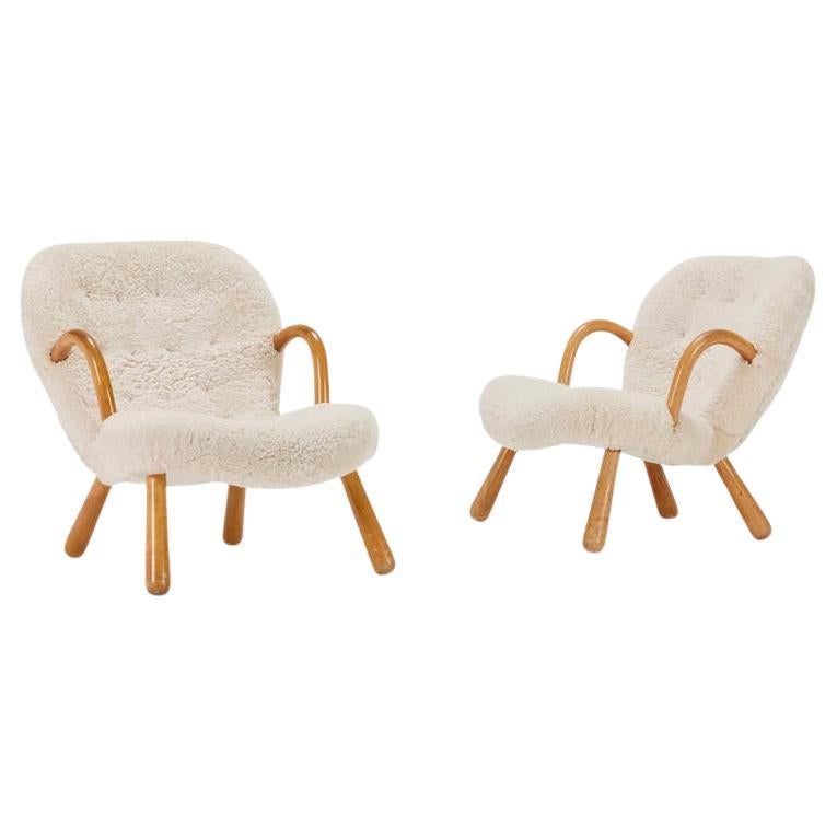 Arnold Madsen pour Madsen & Schubell, rare paire de chaises Clam avec accoudoirs et pieds en bouleau et récemment recouvertes d'une luxueuse peau de mouton bouclée ivoire ou de shearling ornée de boutons en cuir de chameau, Danemark, 1944. Ces
