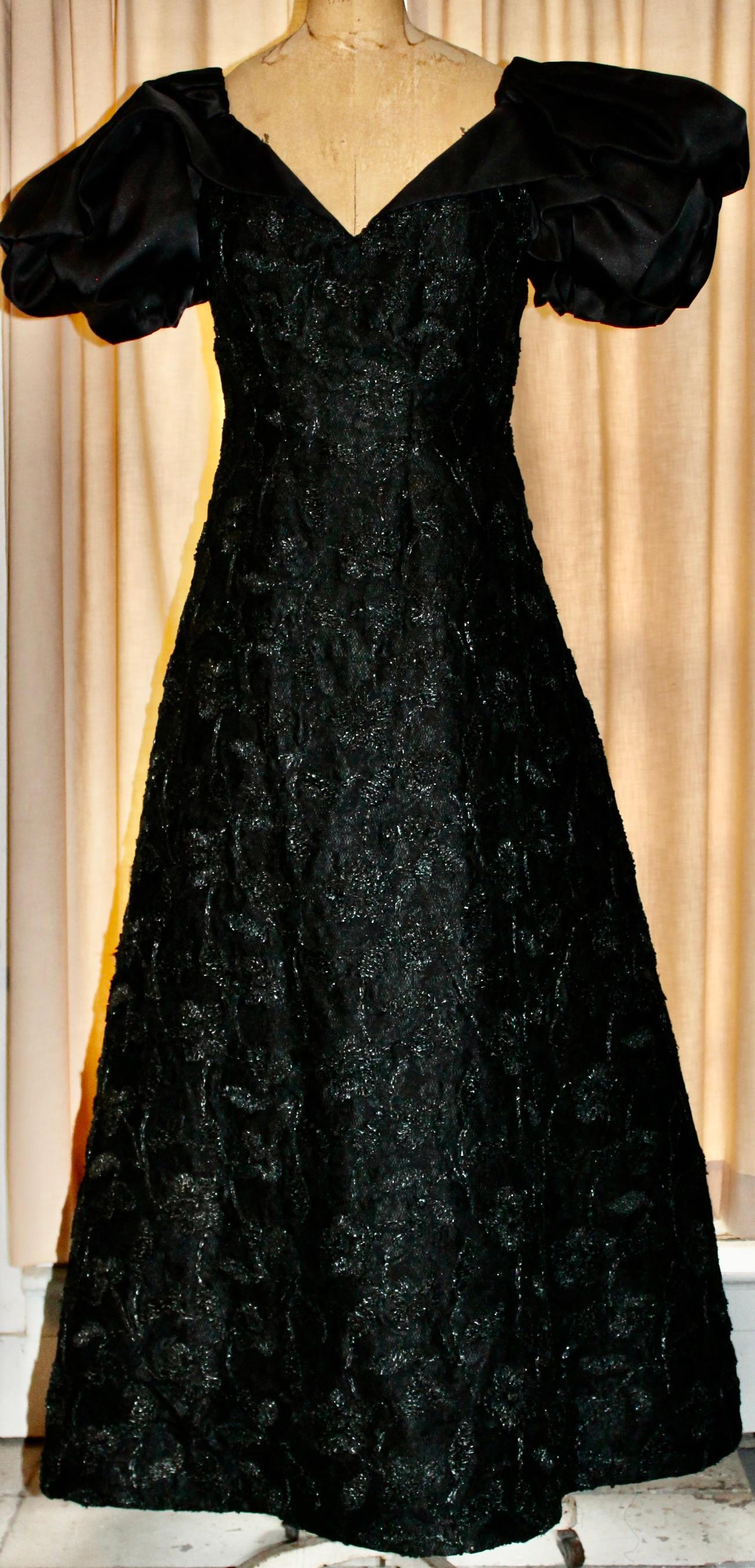 A classic formal A line gown with black silk puffy shoulders. Embroidered overall with 3 dimensional  crepe like flowers  Though marked US 12, with 28