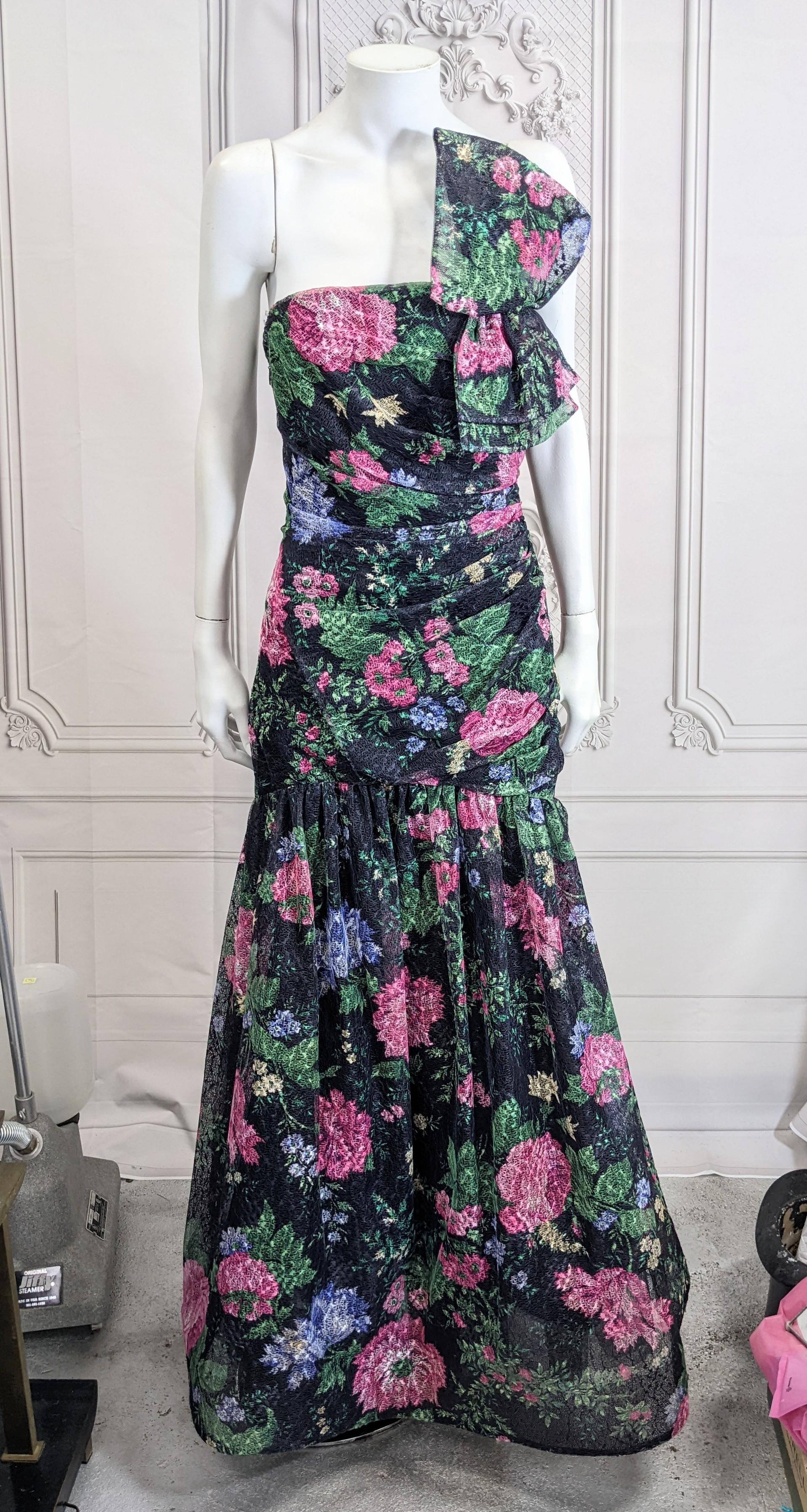 Arnold Scassi Ruched Strapless Floral Lace Net Gown with focal bow and large skirt with petticoats from the 1980's.  A stiffened floral printed lacey net is used in the long shaped gathered bodice which opens to a full skirt with petticoats