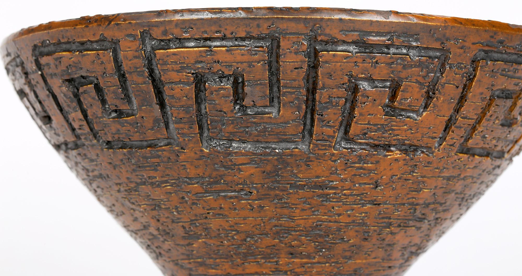 A very stylish large mid-century Finnish Brutalist art pottery bowl with a key pattern design and with a textured brown finish by Arnold Wiigs Fabriker (1943-1977). The bowl stands on a narrow rounded column shaped foot with a wide open rounded top