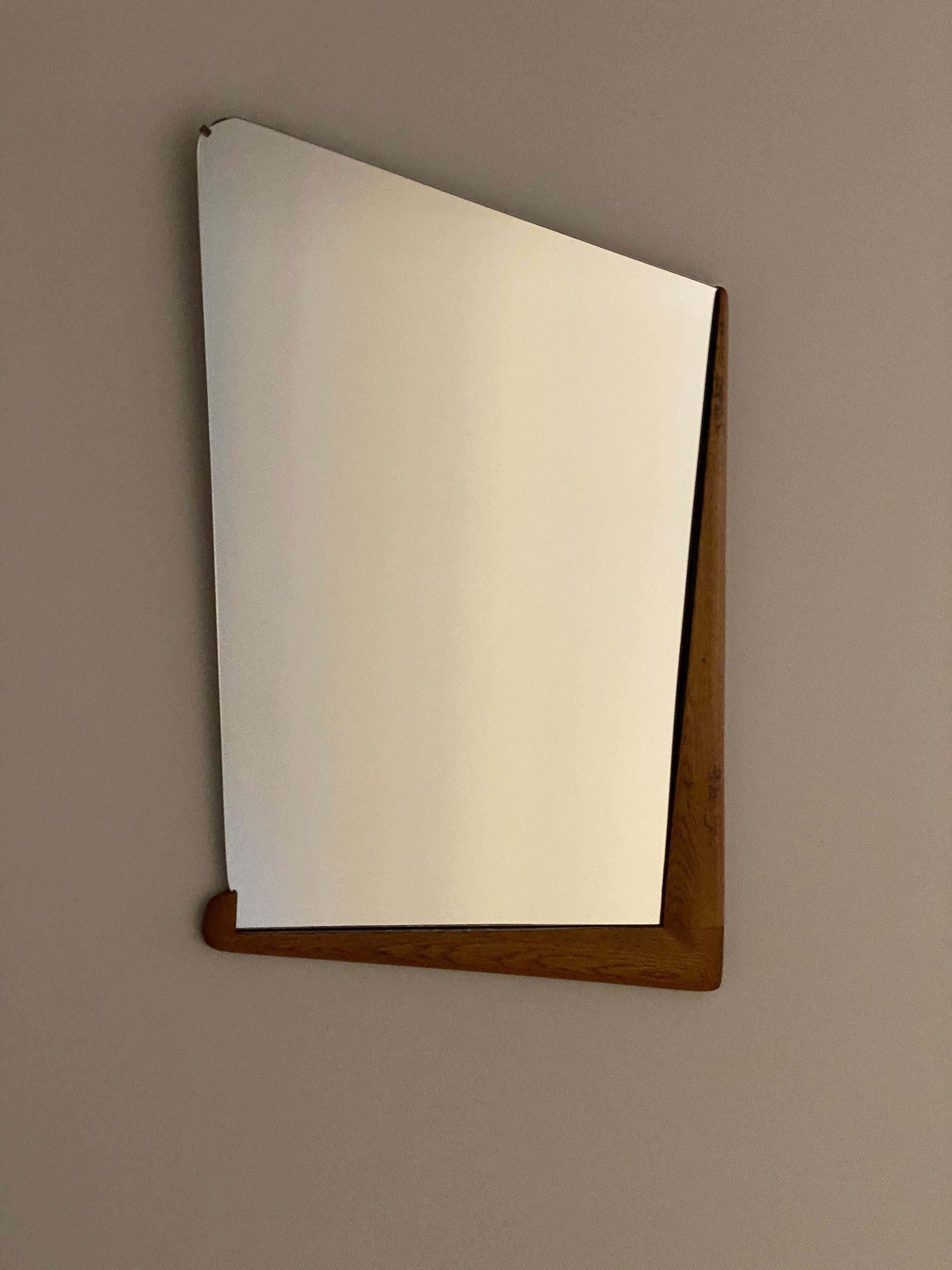 A highly modernist and sculptural asymmetric wall mirror. Produced and designed by Arnoldi Design, Sweden, 1950s. In sculpted and stained oak, black-painted inside trim, original custom-cut glass. Wood appears slightly darker in images than in