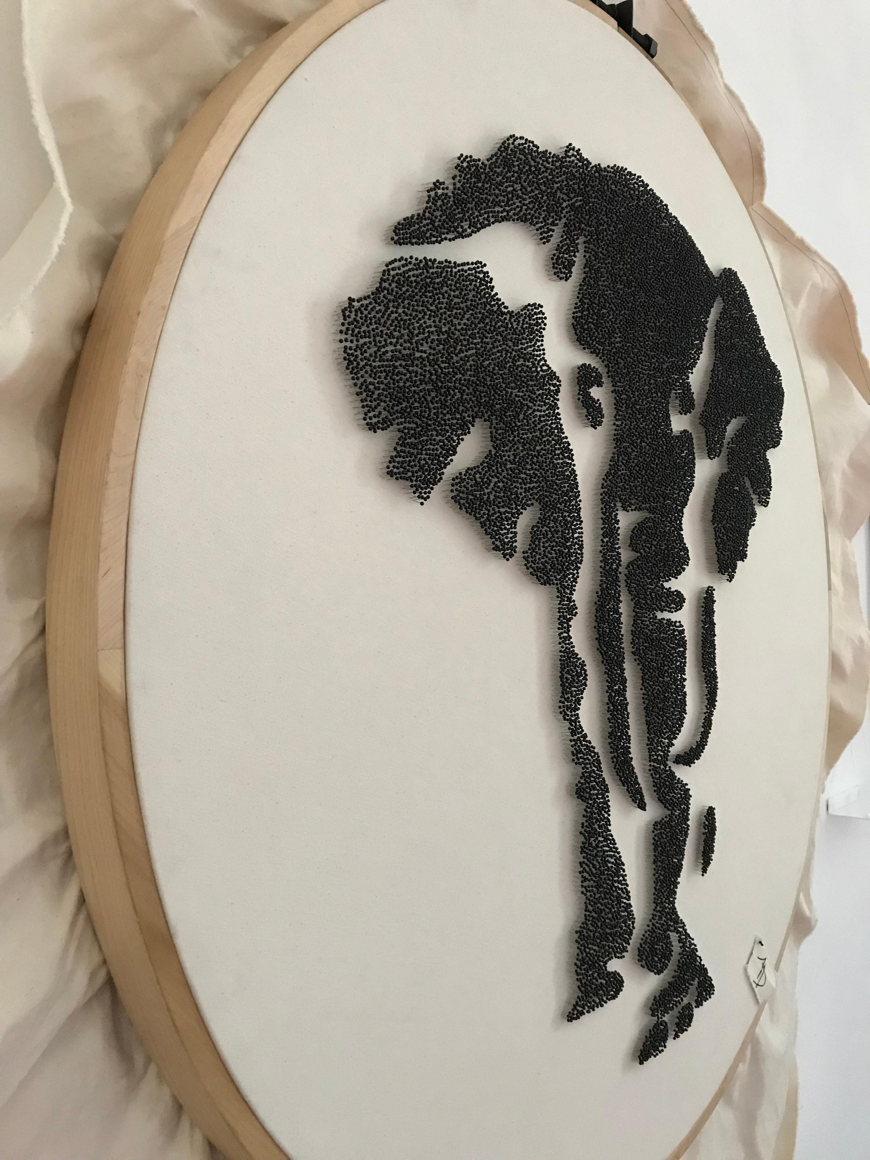 Unique elephant silhouette made with 22,540 black pins. One by one, the pins were carefully placed and were recycled from an antique textile factory. 
This circular frame was handmade with solid wood, the artist carved the wood till she got the