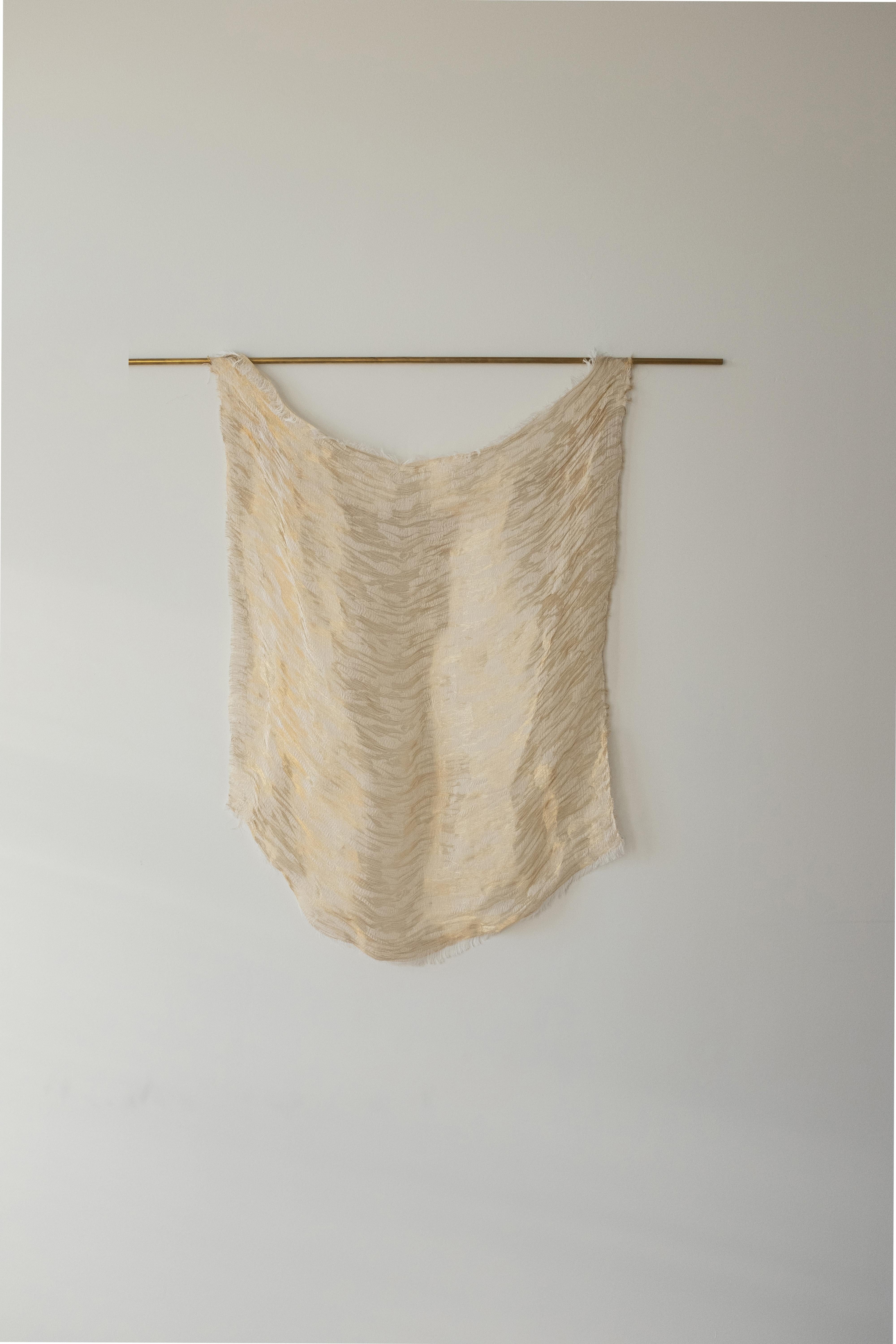 Arpeggi by Nathalie Van der Massen 
Dimensions: 100 x h 70 cm
Materials: Brass, bio cotton. 
Technique: Manually woven. Hand-crafted.

Arpeggi is a woven tapestry that plays with transparency and layers. With accents in brass threads that