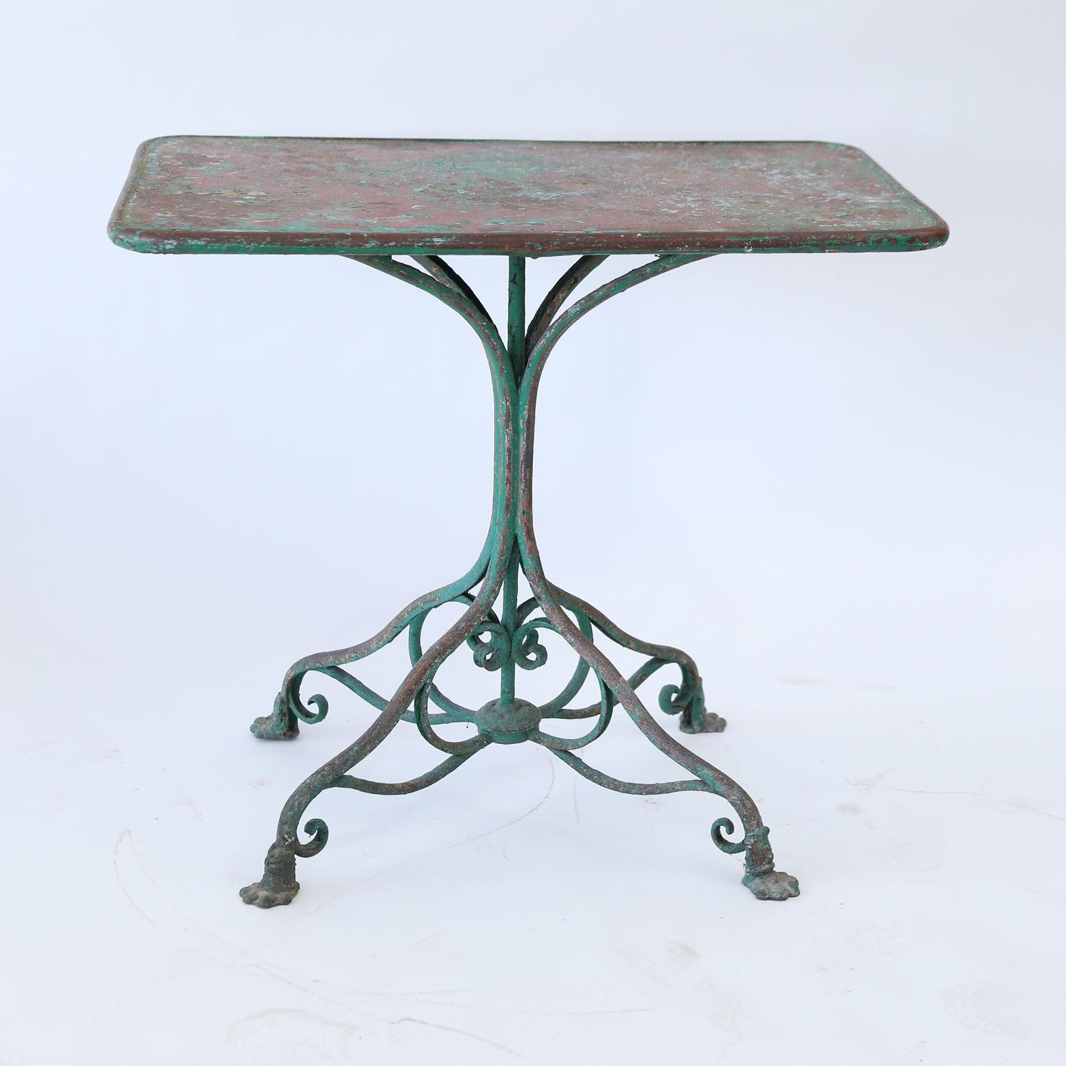 Arras iron garden table, circa 1900-1920, rectangular top raised upon a slender pedestal comprised of four round iron bars that gracefully radiate out to form a quadriped base, decorated with scrolled iron embellishments and supported by four iron