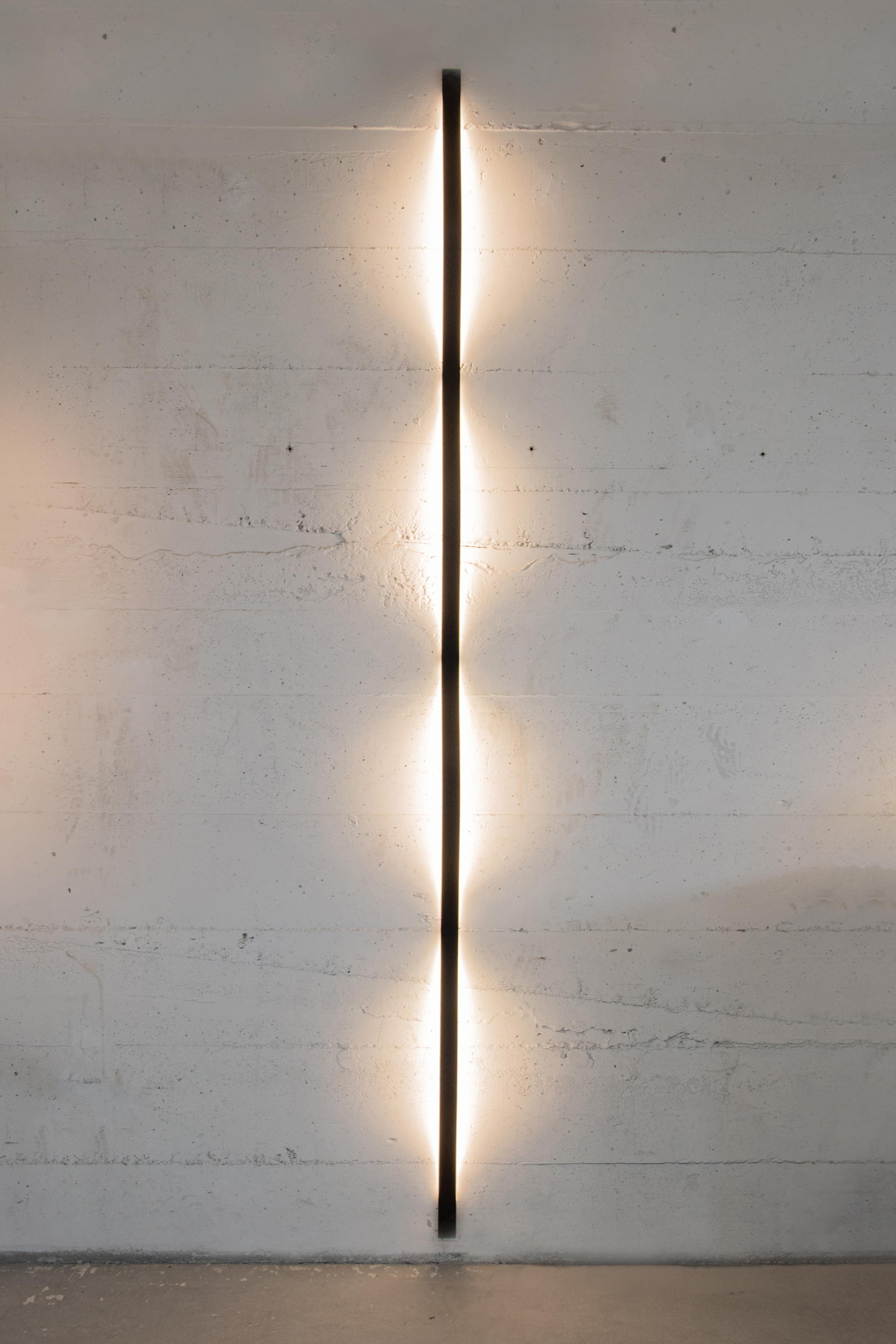 Les lampes Steele sont fabriquées à partir de bandes d'acier à ressort recouvertes d'une couche de poudre. En fixant la lampe au mur ou au plafond à l'aide de petits supports, la forme d'onde apparaît sous l'effet de la tension du