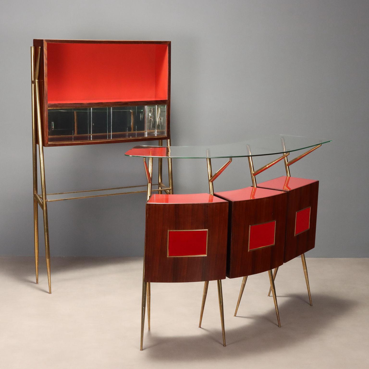 Mobile bar vintage di manifattura italiana del XX secolo composto da banco con struttura in ottone, corpo in legno con impiallacciatura in mogano e legno esotico, vani contenitori a giorno con ripiani sul retro e formelle decorativo sul fronte in