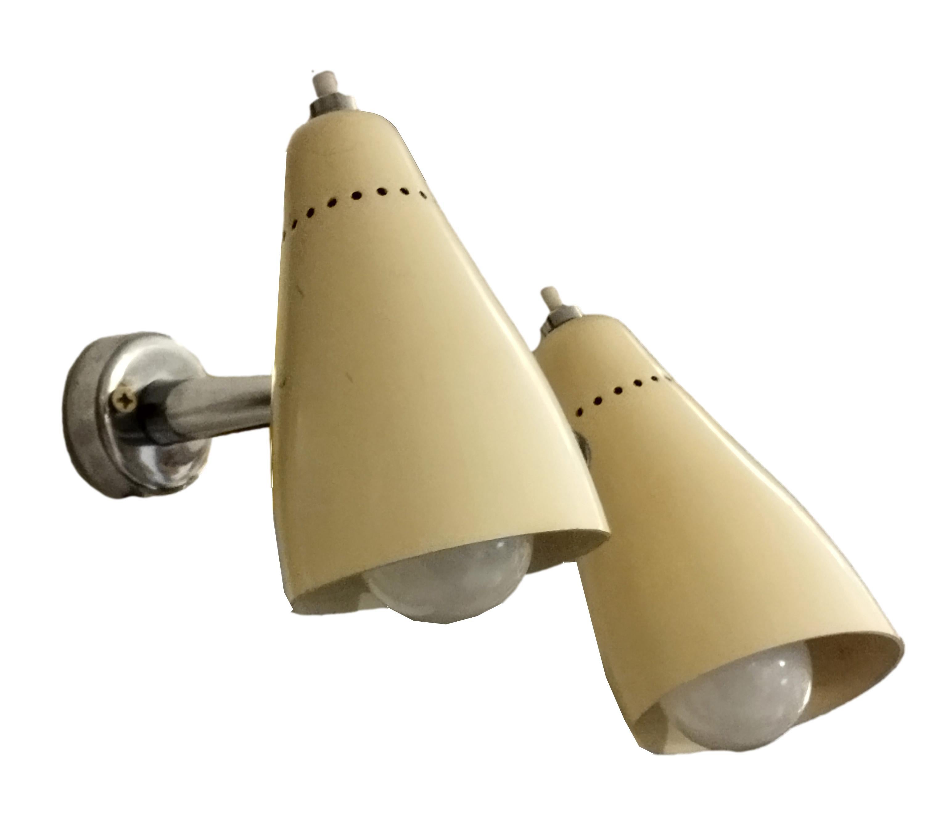 Gilded brass circular base wall sconce with conical stem ending in two spherical joints that accommodate two cream lacquered metal conical reflectors.
