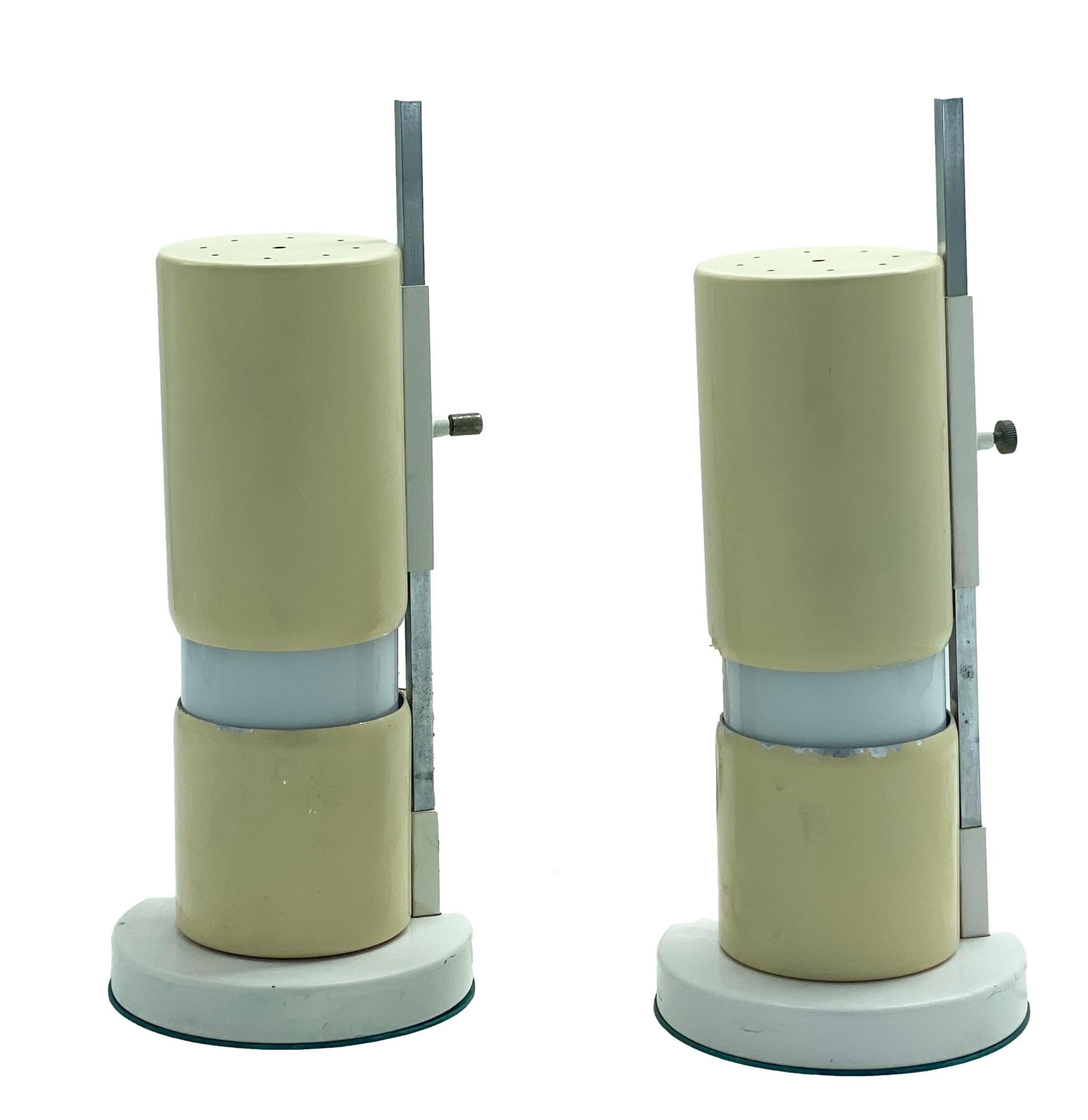 Pair of adjustable table lamps with constructivist form is attributed to Italian designer Angelo Lelli. The cylindrical ivory metal table lamp has a sliding canopy on a small vertical steel arm, on a circular base of steel and white opaline glass.