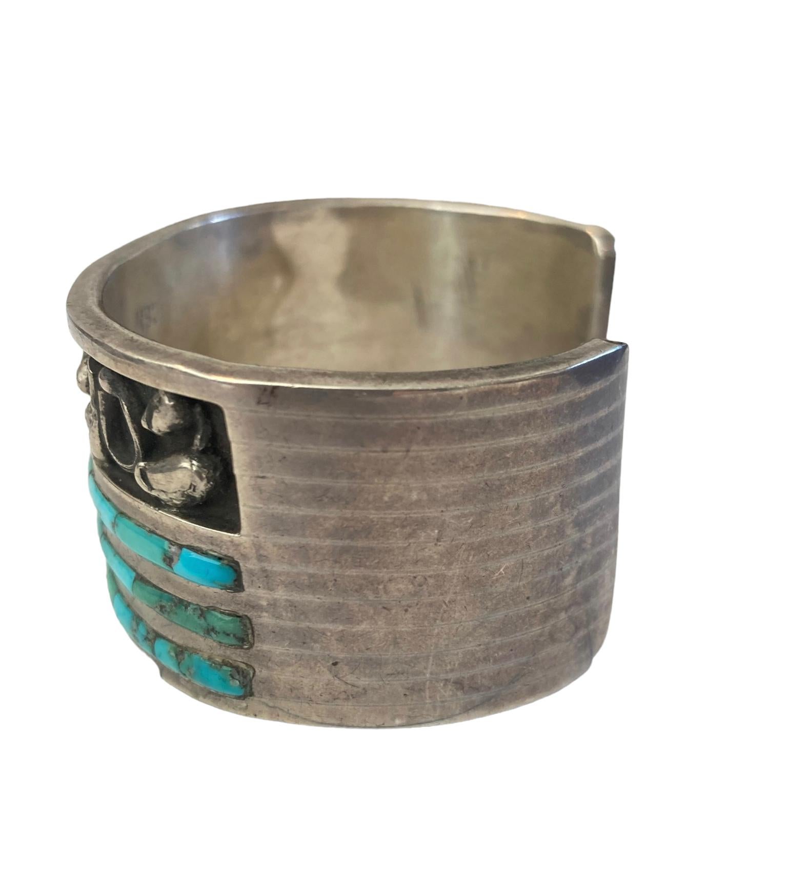 This Arresting Zuni Chester B Mahooty Sterling Silver and Turquoise Cuff Bracelet will stop you in your tracks. The turquoise inlay set between thick bands of sterling with an abstract sterling silver design above it is gorgeous. The bracelet is