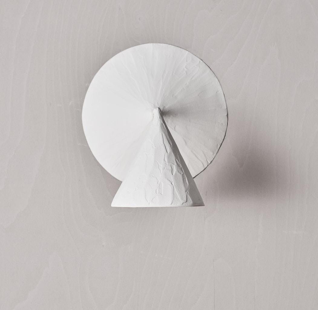 The Arrow wall light offers a distinctive and modern aesthetic whilst retaining a hand crafted textured quality. 
The playful design of the two cones create a sculptural and artistic form, an emphasis on the relationship of the perpendicular cones,