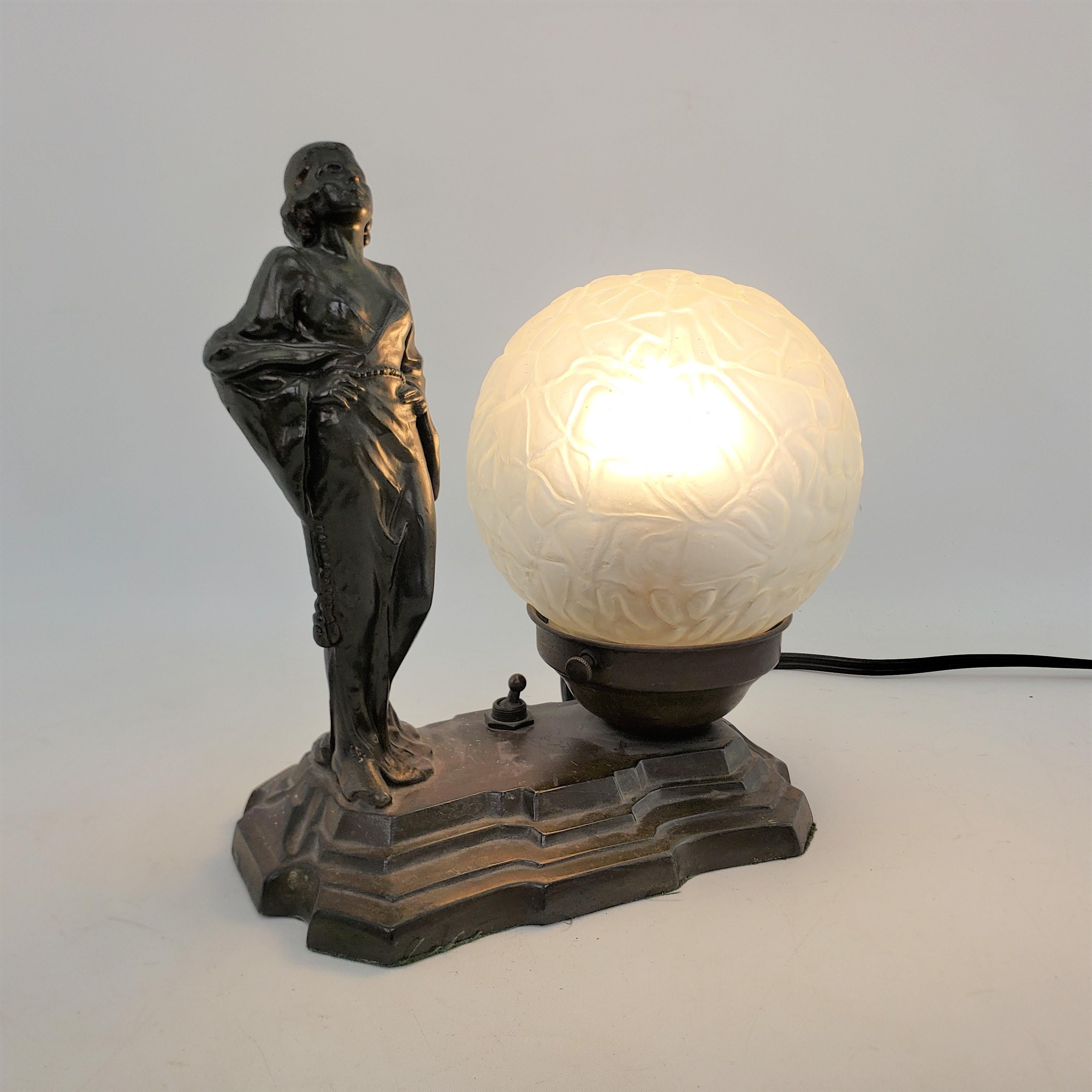 This antique table or accent lamp is unsigned, but presumed to have originated from the United States and date to approximately 1920 and done in the period Art Deco style. The lamp is composed of a cast spelter with a bronze patination and depicts a