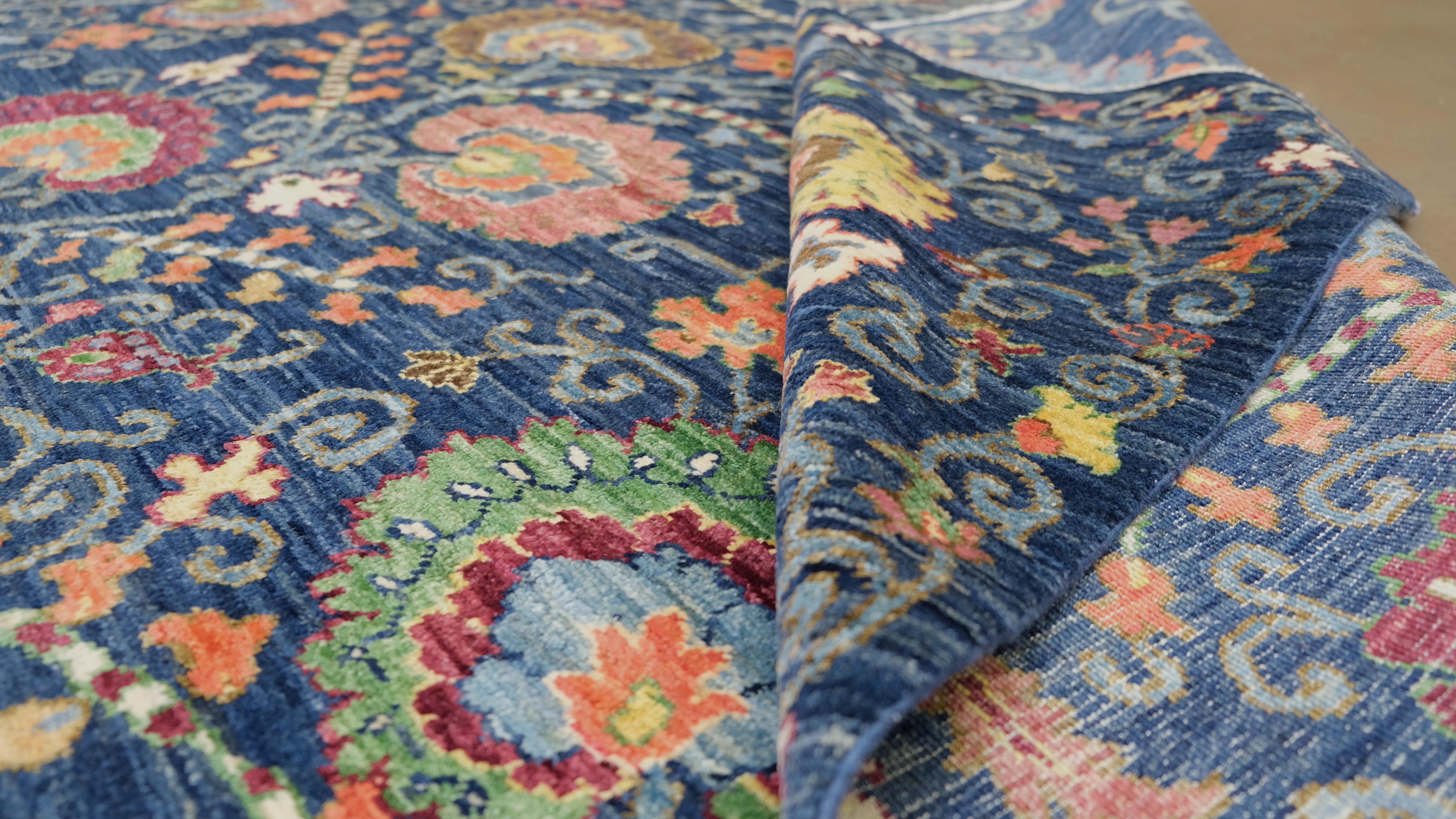 Verschönern Sie Ihren Raum mit diesem exquisiten, handgeknüpften Wollteppich mit lebhaftem und kompliziertem Blumenmuster. Ein sattblauer Hintergrund bildet einen auffälligen Kontrast zu den farbenfrohen Blumen in Rot-, Orange-, Gelb- und Grüntönen,