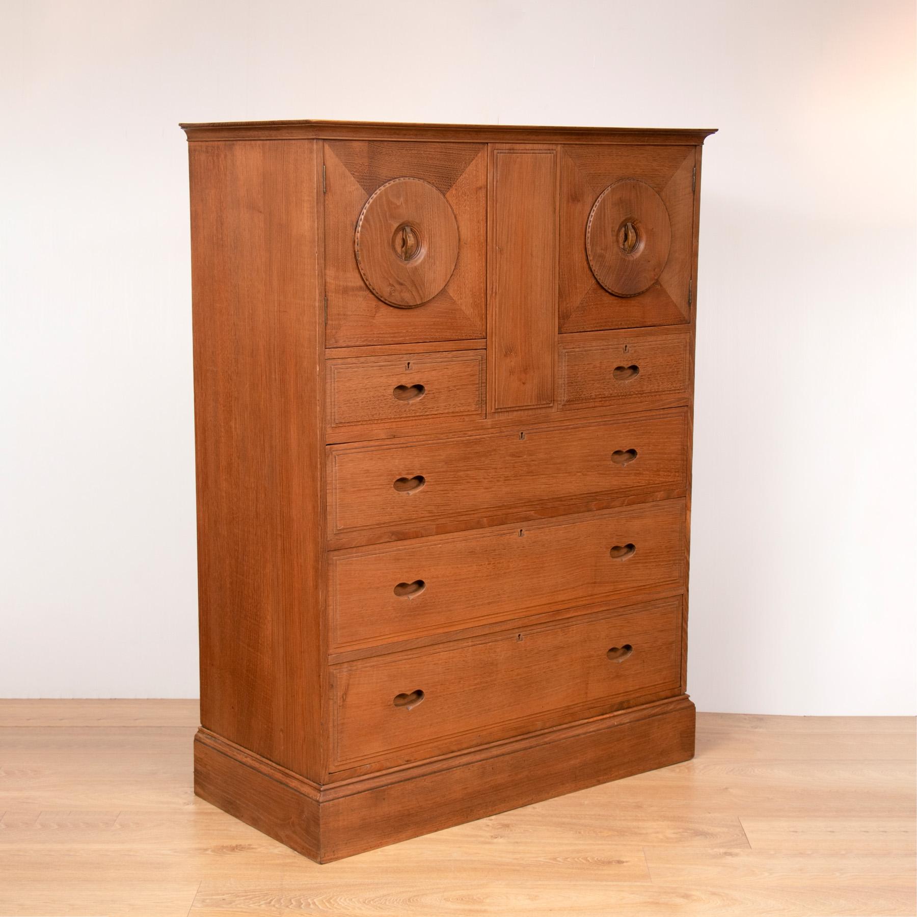 Extremely rare Ambrose heal chestnut owl cabinet with owl eye panelled doors over drawers with pierced heart handles.