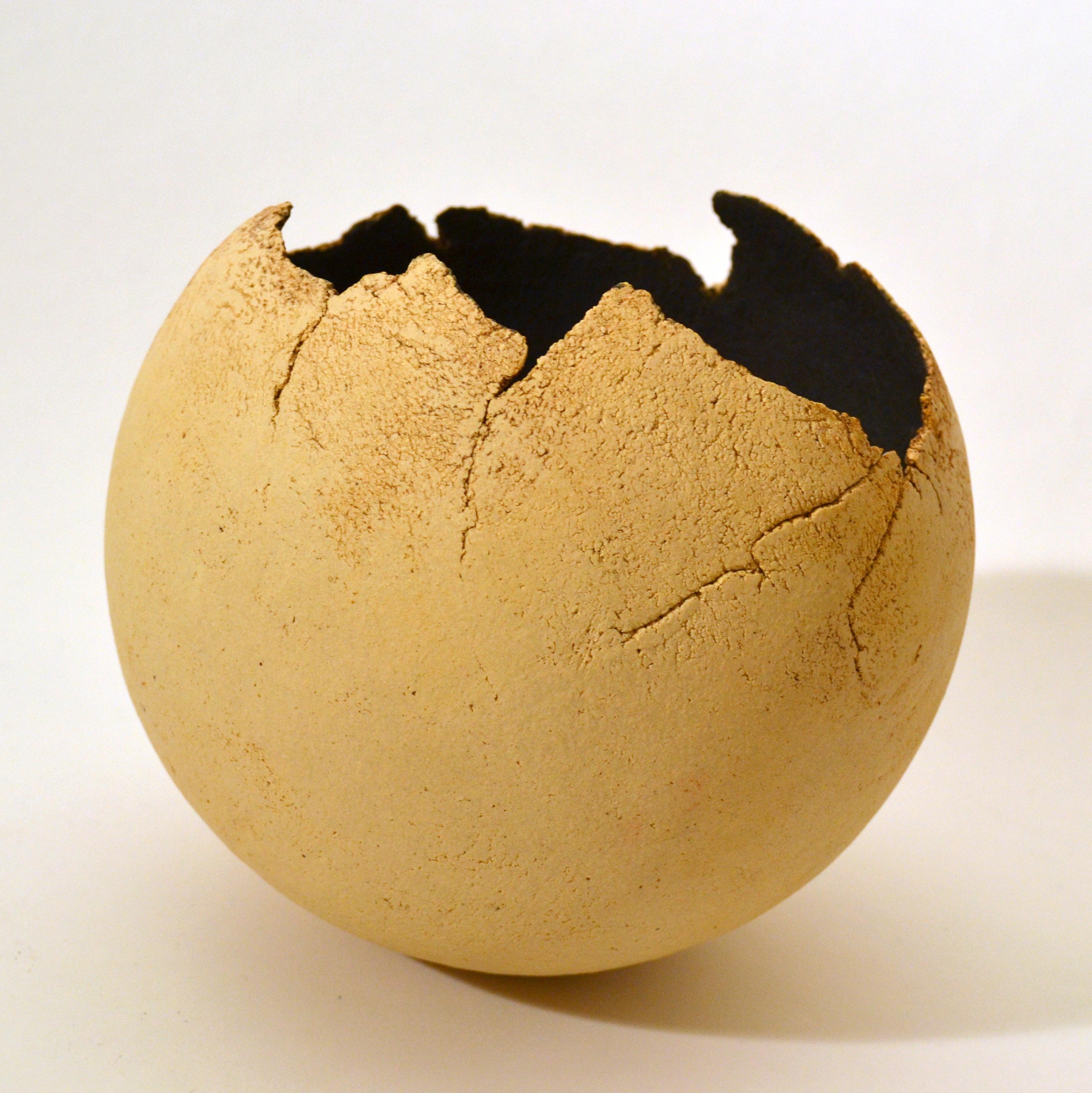 Sculptural round studio pottery decorative abstract bowl by unknown artisan producing this unique Raku fired ball shaped vessel, black inside and unglazed cream outside with the edges as a delicate broken egg shell.
The studio potter is one who is a