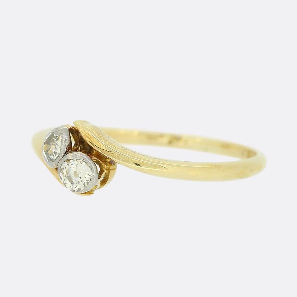 Si tratta di un anello crossover con diamanti in oro giallo 18ct. I due diamanti sono stati incastonati in una pinza di platino e in una fascia d'oro giallo da 18 carati. Entrambi i diamanti sono perfettamente assortiti per colore, purezza e