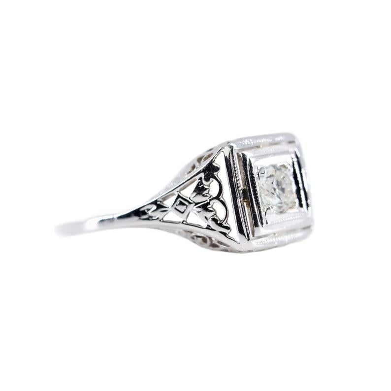 Aston Estate Jewelry Presents:

A vintage Art Deco diamond engagement ring in 18 karat white gold. Centered by a 0.25 carat old European cut diamond of H color and VS2 clarity. Completed by pierced filigree work and engraved detailing