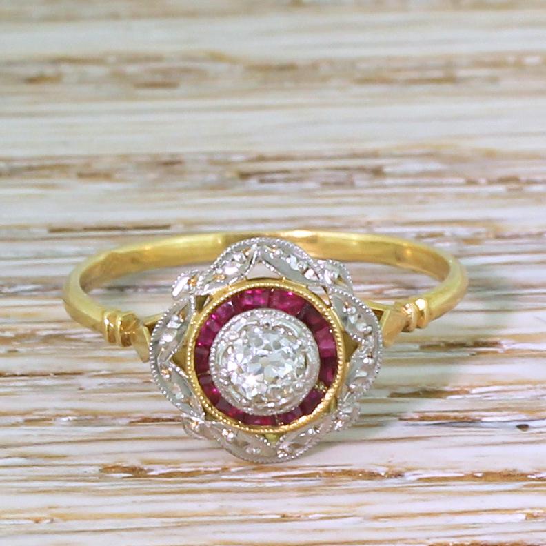 There can't be many rings as sweet as this old cut diamond and ruby target ring. The centre diamond, of approximately 0.30 carat, is rubover set in milgrained white gold, and surrounded by an unbroken circle of bright pinkish red calibré cut rubies.