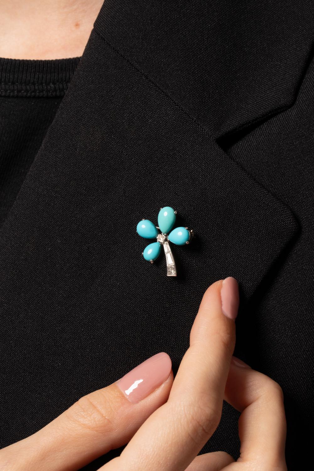 This delightful Art Deco brooch is designed in a delicate flower like shape. Crafted entirely in platinum the design features an arrangement of four pear shaped cabochon cut turquoise stones. The turquoise vary in size, with one larger stone at the