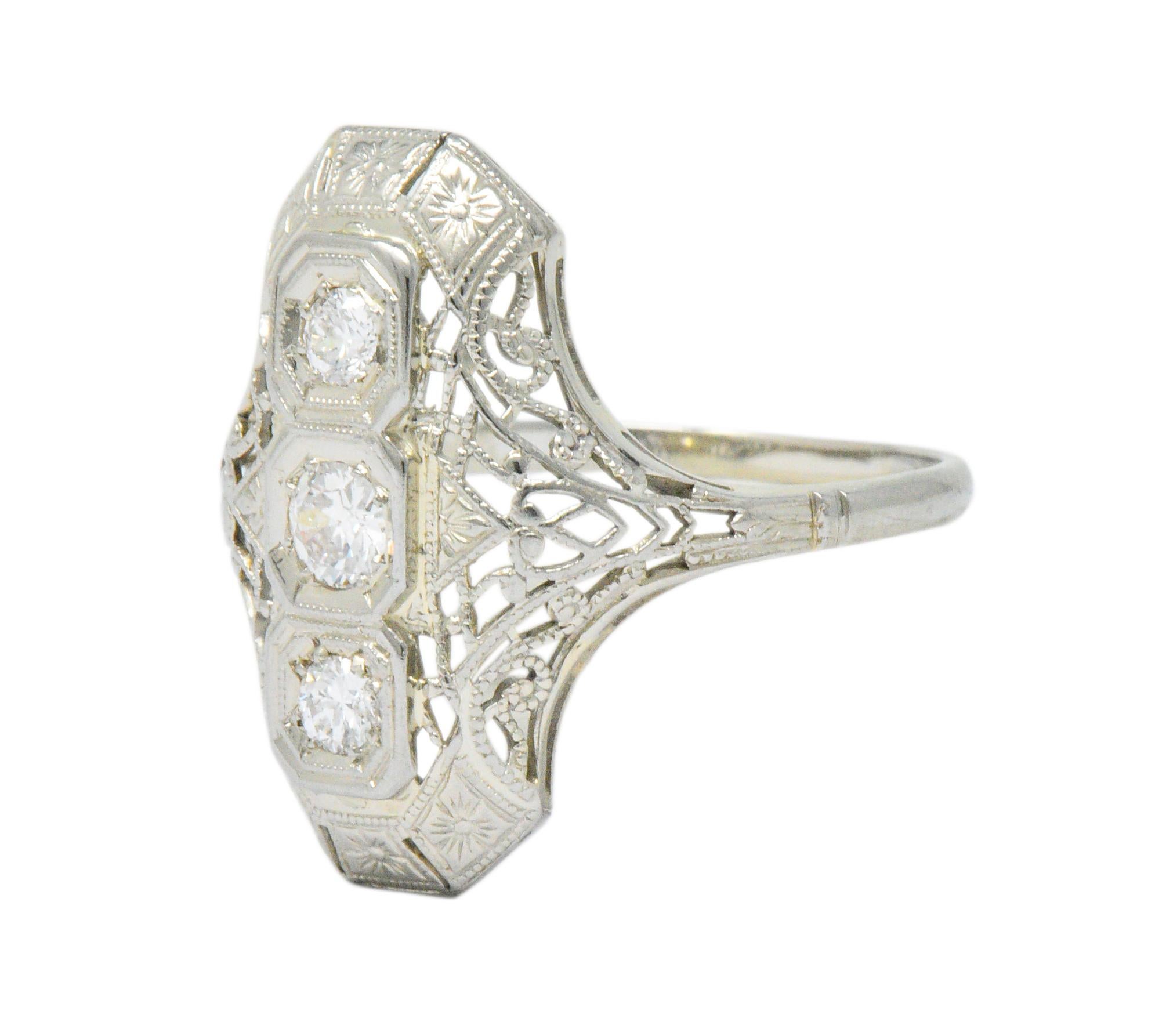Dinner style ring centering three cushion forms set North to South with three old European cut diamonds

Weighing approximately 0.40 carat with G to I color and VS to SI clarity

Completed by pierced lattice work, milgrain detail, and deeply