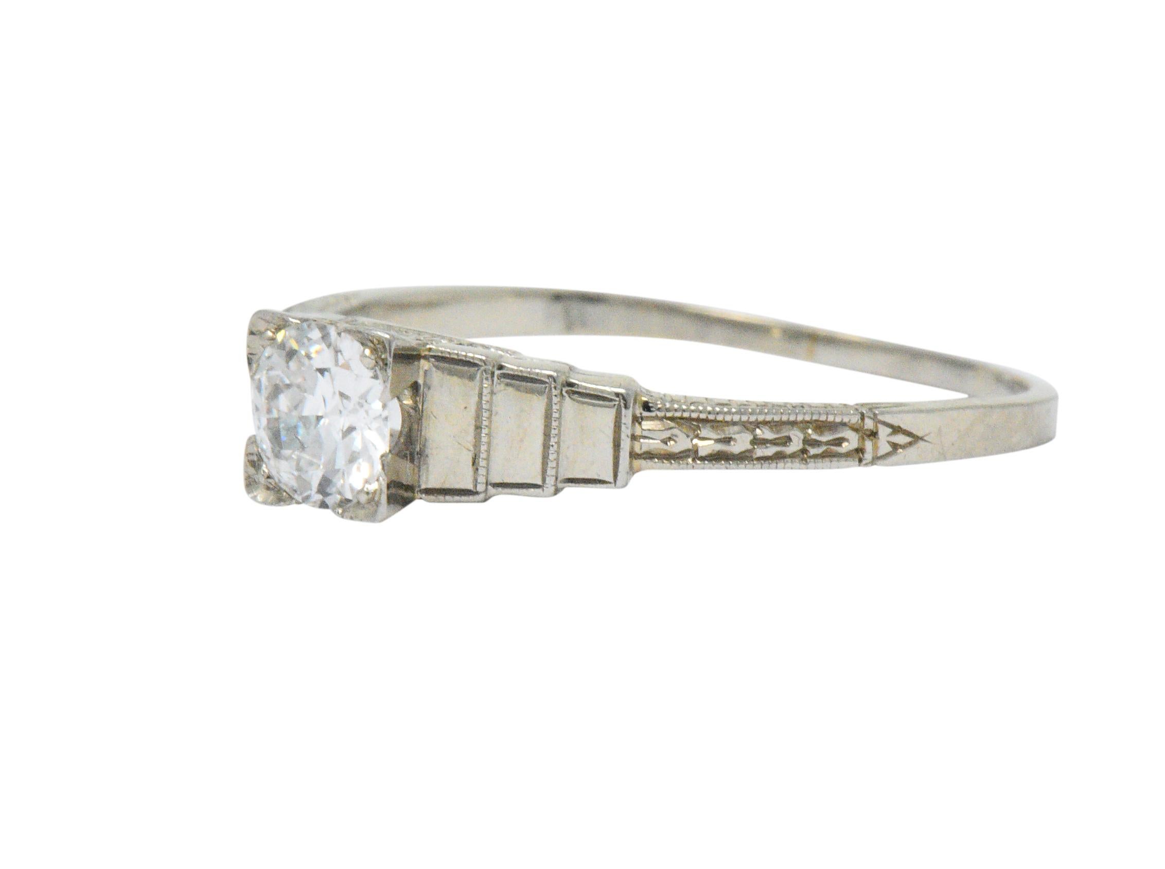 Centering an old European cut diamond, set in a square form head, weighing approximately 0.40 carat; G color with SI clarity

Flanked by a stepped rectangle motif, graduating in size

Completed by a deeply engraved foliate shank

Ring Size: 8 &