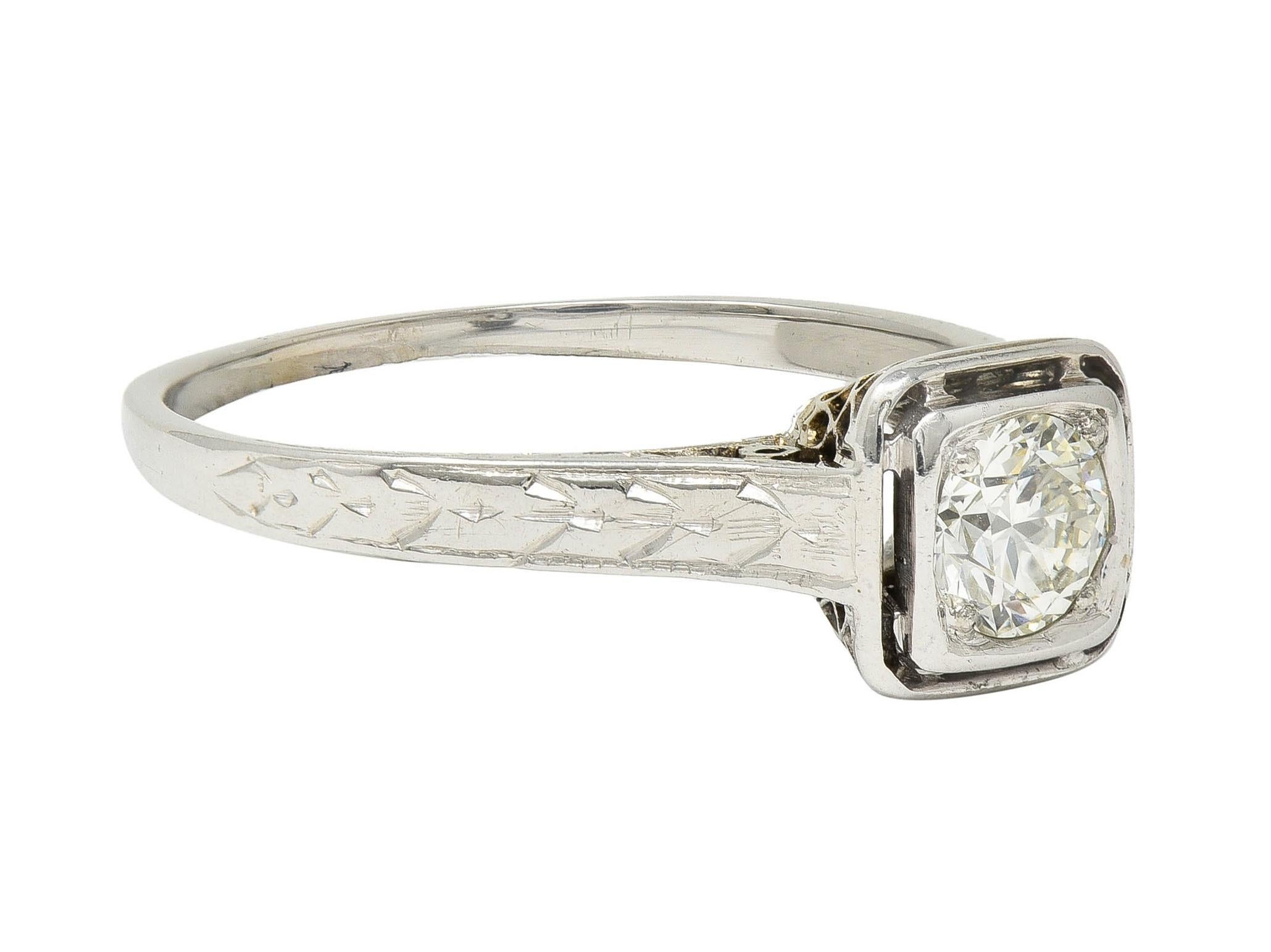 Centering a transitional cut diamond weighing approximately 0.40 carat -  J color with VS clarity
Bead set in cushion shaped form with a pierced halo surround and  intricate trellis gallery
Flanked by cathedral shoulders engraved with a wheat