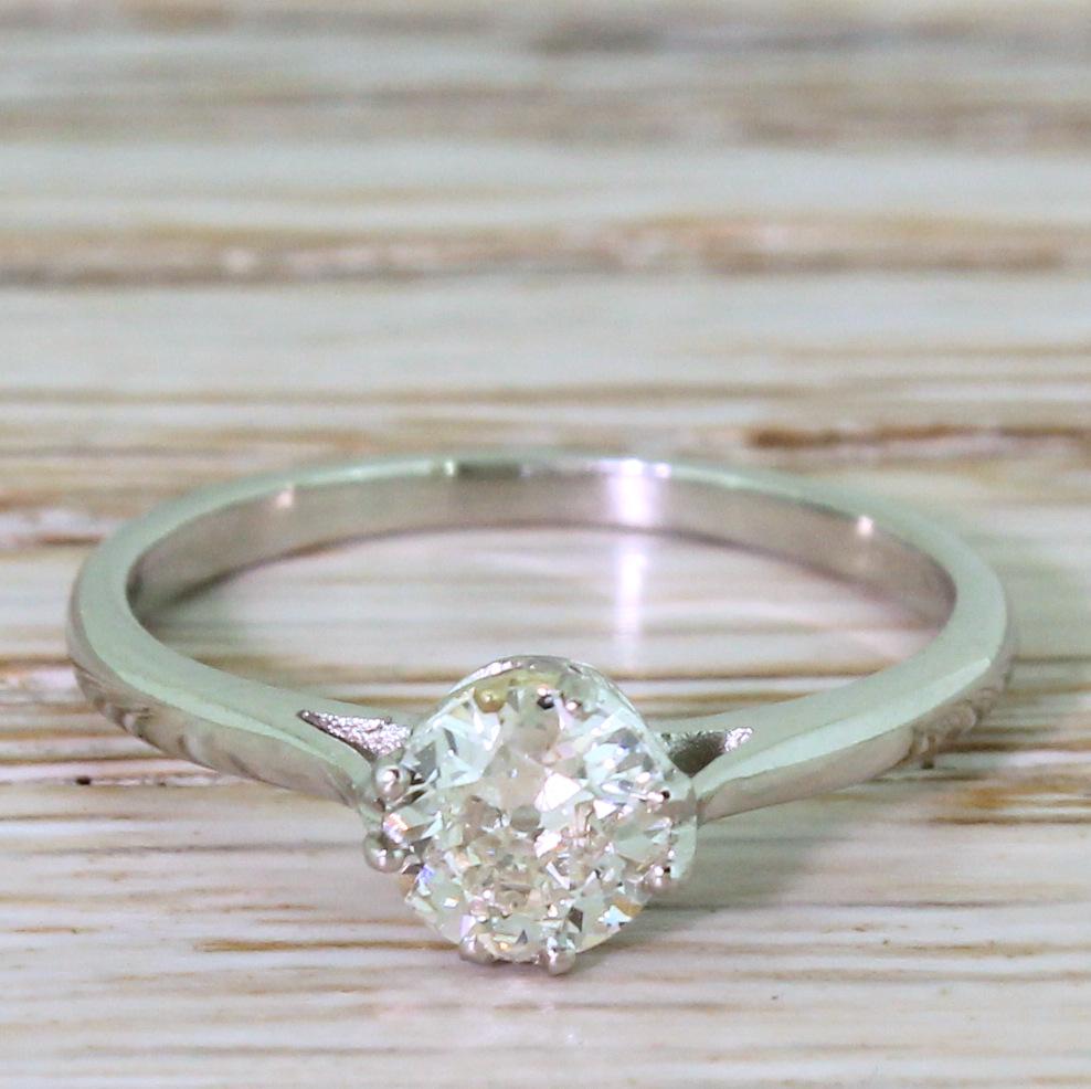 A wonderful vintage engagement ring. The old European cut diamond in the centre is high white and bright, and is secured in by four split-claws with sweeping detailing in the gallery. On a slim and plain D-shaped platinum shank. Refined and