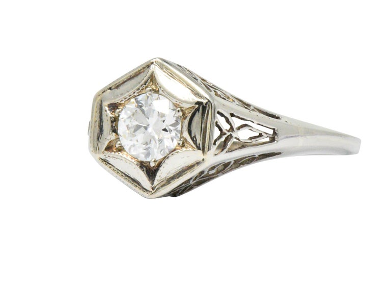 Centering an old European cut diamond weighing approximately 0.47 carat, G color with VS clarity

Graver set in a hexagonal head as a tantalizing starburst motif

With pierced filigree shoulders and gallery

Tested as 14 karat white gold

Circa: