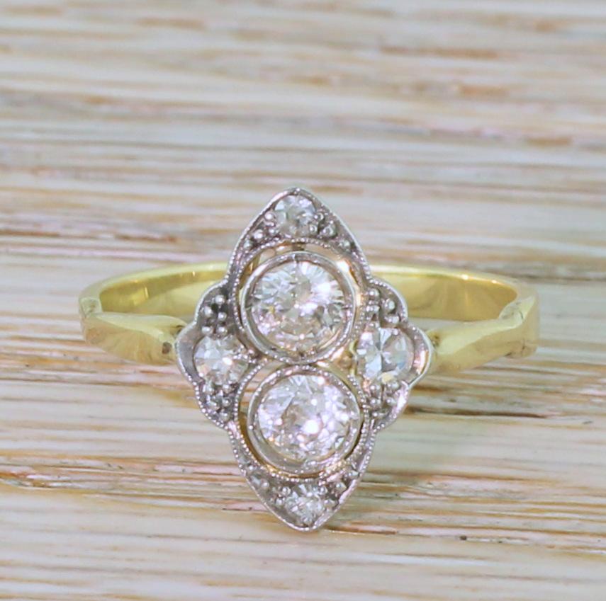 A super cute Art Deco diamond ring. The two bright and lively transitional cut diamonds in the centre are rubover set in milgrained platinum, and ‘float’ within a beaded, navette shaped gallery which sits nice and low to the gallery. Four smaller