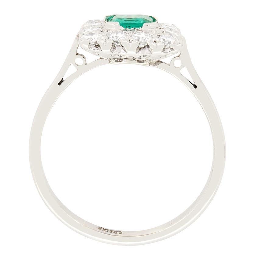 Dieser atemberaubende quadratische Ring, der im Herzen der Art-déco-Ära handgefertigt wurde, zeigt in der Mitte einen leuchtend grünen Smaragd, der von Diamanten im Übergangsschliff umgeben ist. Der Smaragd von 0,50 Karat ist ein Stein im