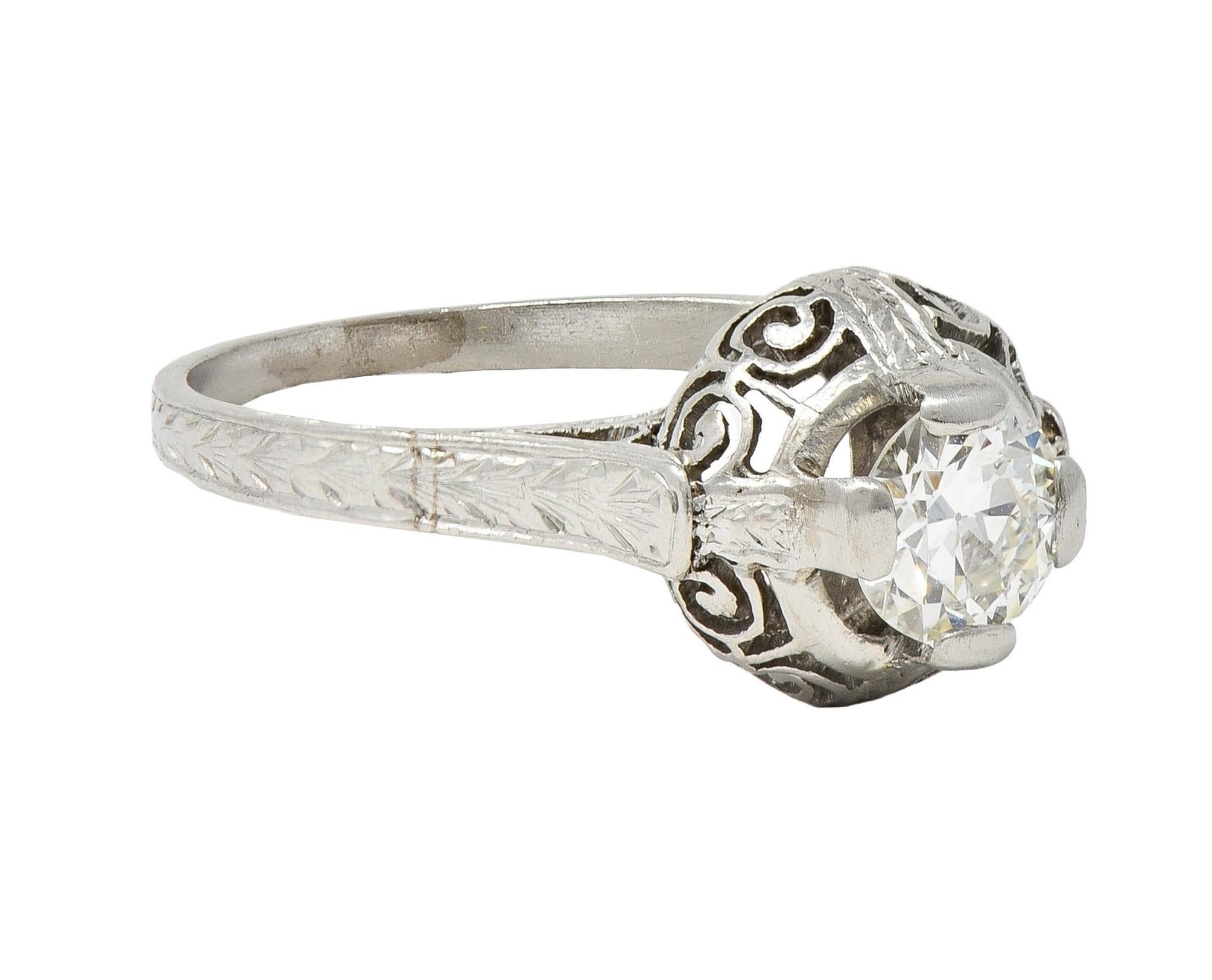 Centering a transitional cut diamond weighing approximately 0.52 carat - I color with VS clarity
Set by wide prongs with a puffed round gallery pierced with scroll motif
Flanked by cathedral shoulders engraved with wheat motif
Wheat motif continues