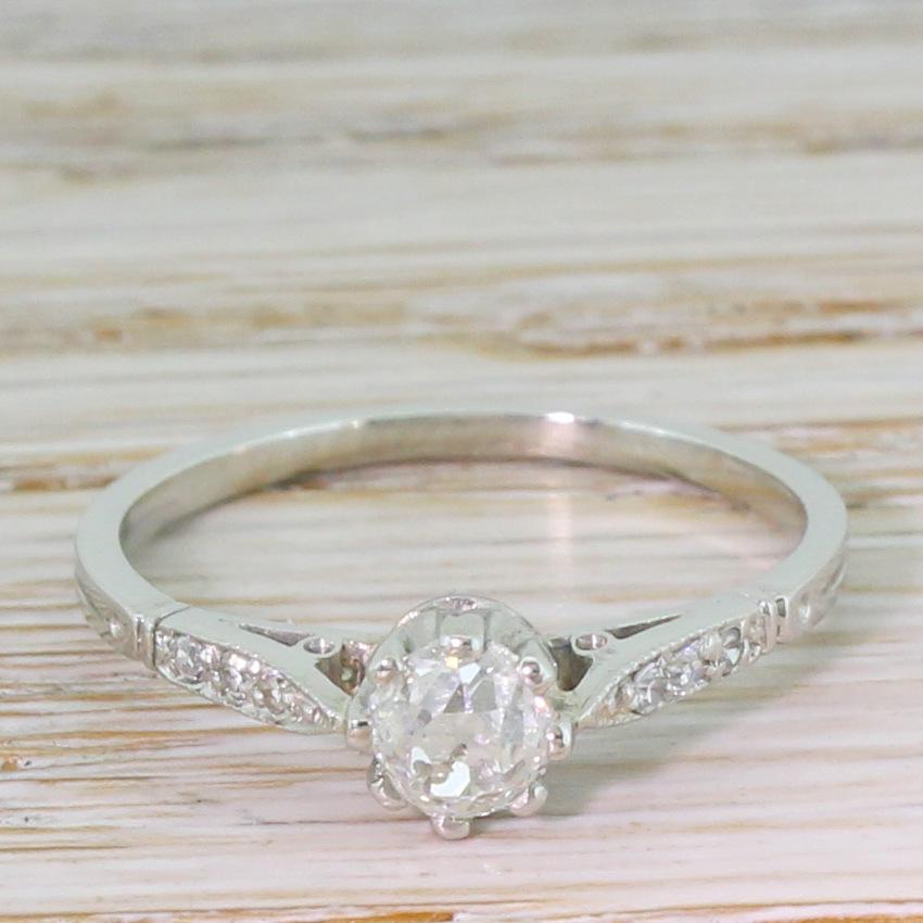 Just the prettiest antique solitaire ring. The old mine cut diamond in the centre is exceptionally white, internally clean and impressively vibrant. The stone is secured in an eight-claw coronet collet leading to diamond-set tapering shoulders to a
