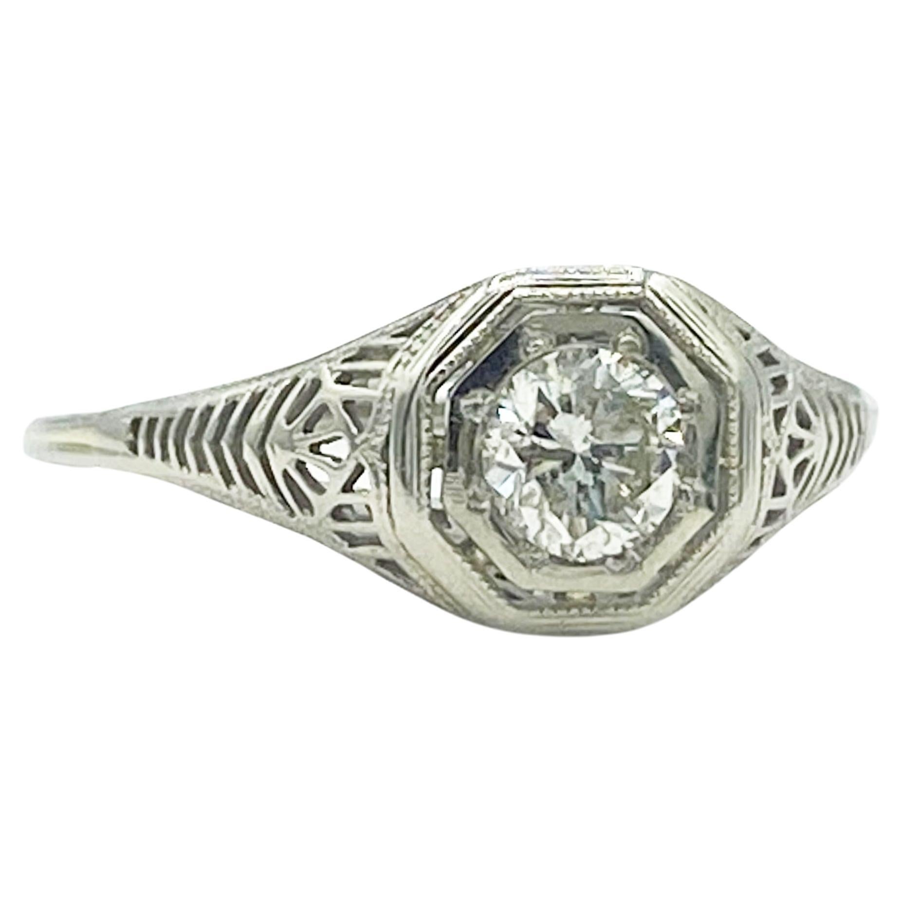 Unique antique Art Deco diamond 18k white gold engagement ring with a finely detailed shank. The Old European cut diamond solitaire is placed in an octagonal setting. The shoulders and shank have impressive milgrain and openwork filigree that
