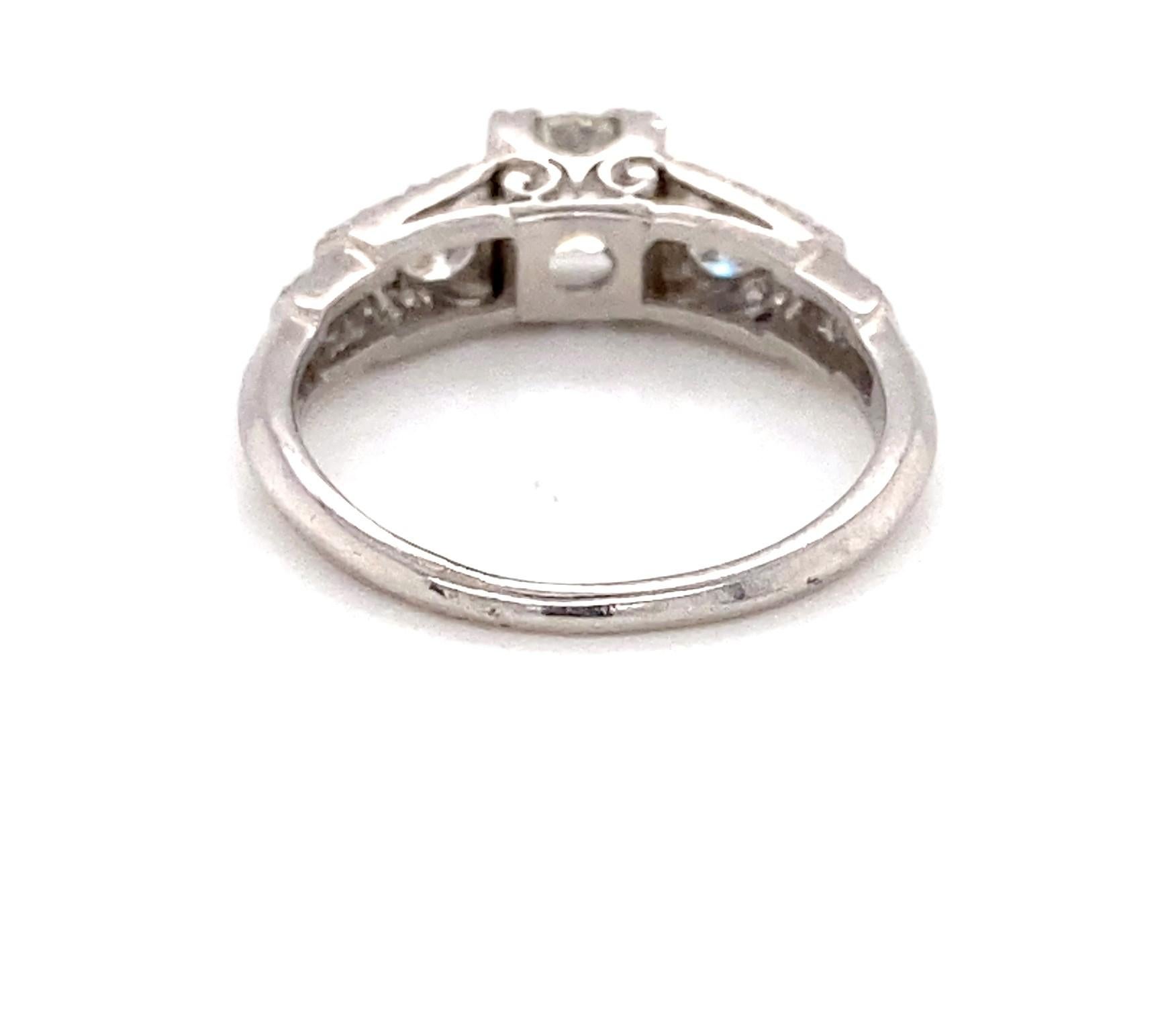 This Art Deco platinum engagement ring, circa 1930s, features a scintillating center approximately 0.59 carat old European-cut diamond of I - J color grade and I1 - I2 clarity grade. Set in four triple prongs, it is flanked on either side by one