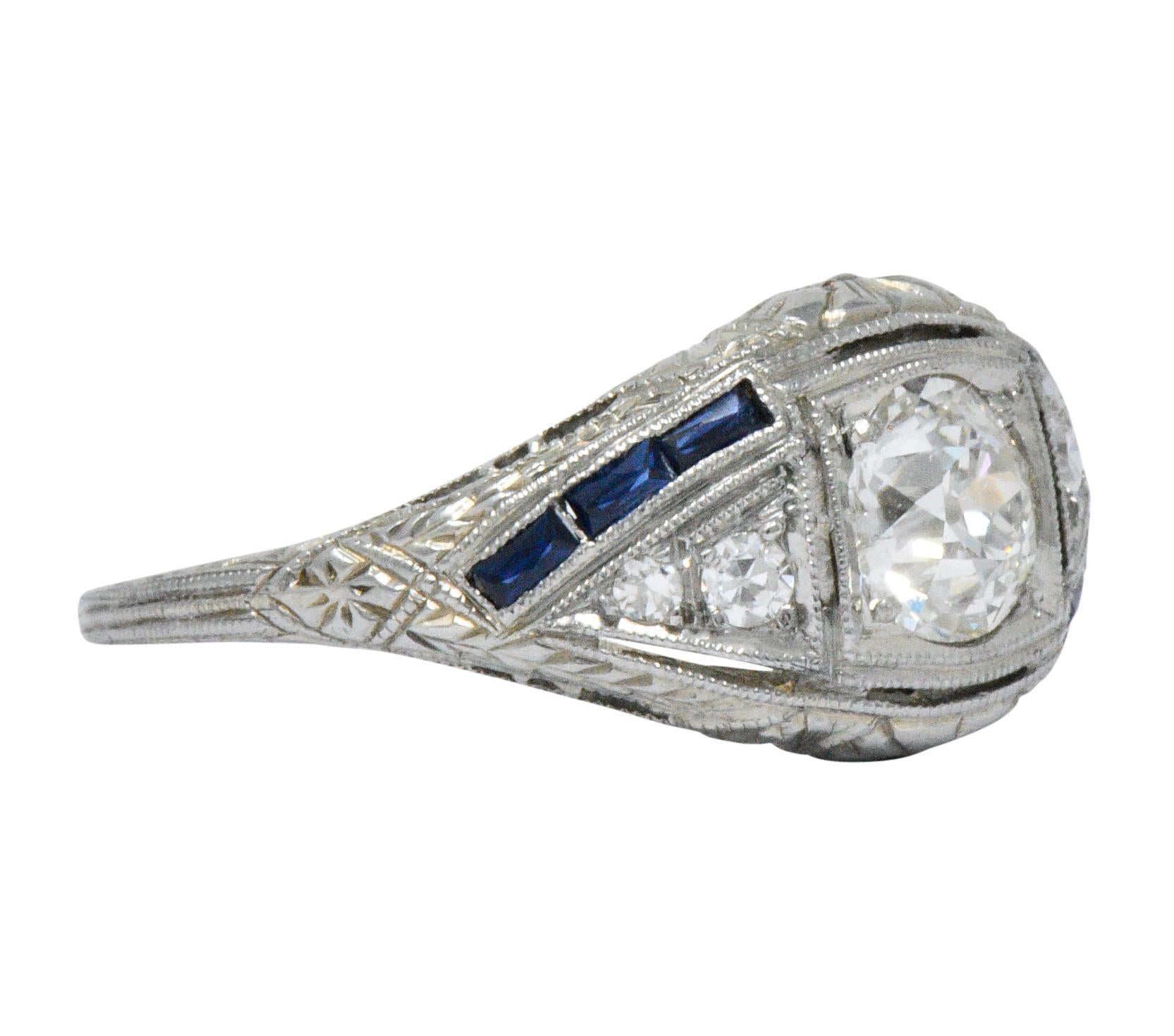 Centering an old European diamond weighing approximately 0.60 carat, I color with SI1

Flanked by two triangular forms accented by single cut diamonds, eye-clean and white

With two dynamic channels of calibre cut sapphire, bright royal blue in