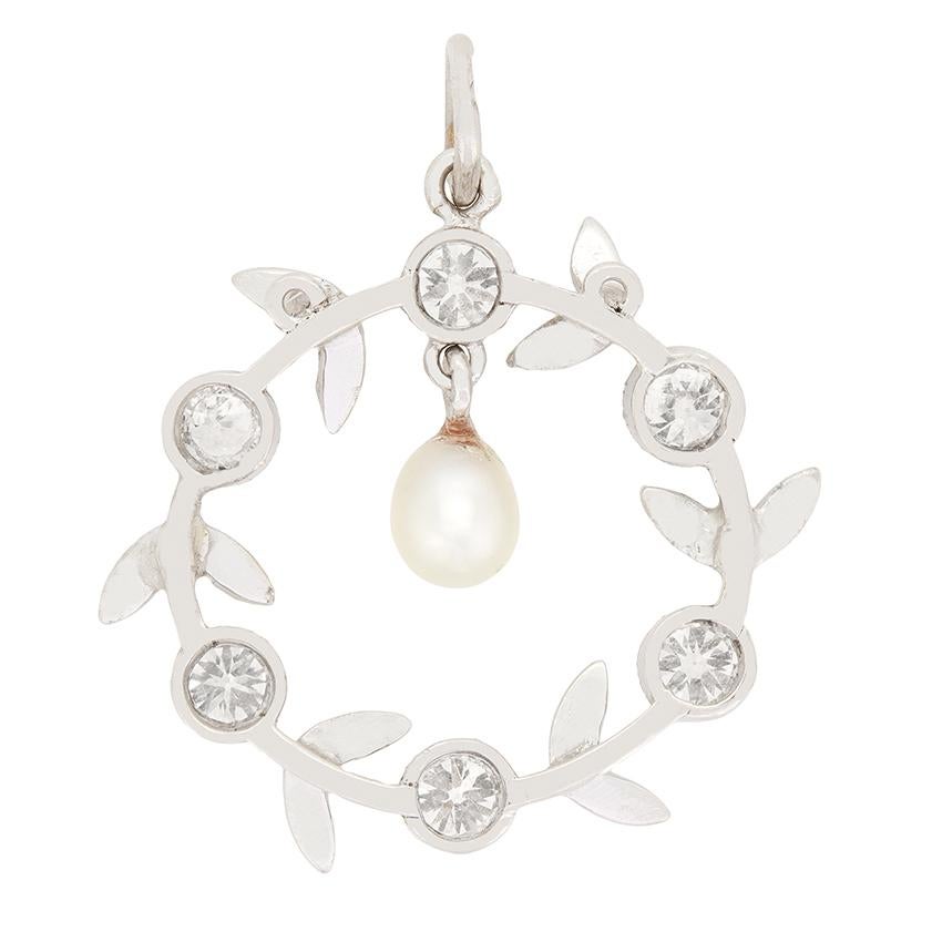 Ce délicat pendentif en diamants et perles a été fabriqué à la main dans les années 1920. Centré autour d'une perle de 4 mm, un cercle de platine est entouré de six diamants sertis entre des motifs de pétales. Chacun des diamants de taille ancienne