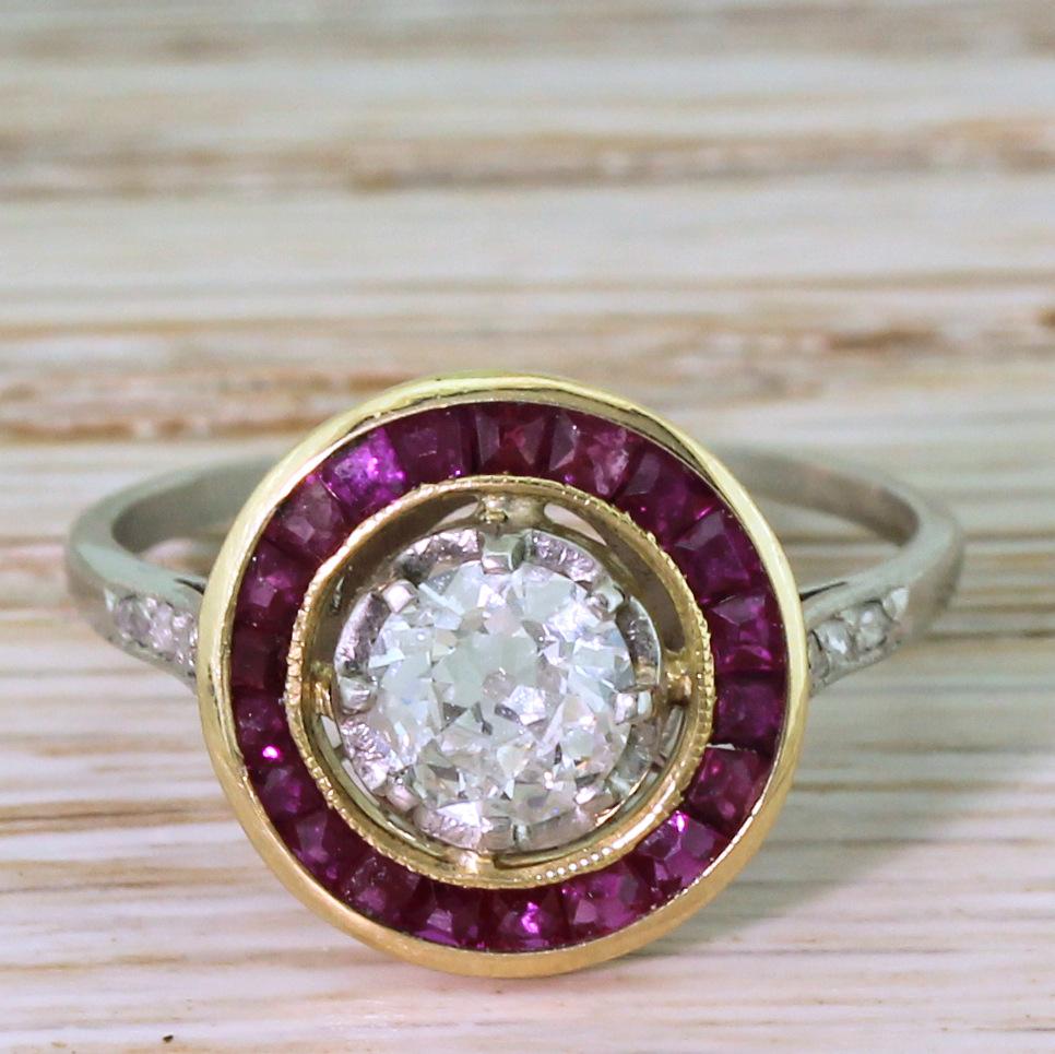A stunning antique ruby and diamond ring. The old cut diamond in the centre, graded by HRD as F colour, is blindingly white and, despite the P1 clarity grading, is clean to the naked eye and impressively lively. The centre stone “floats” within a